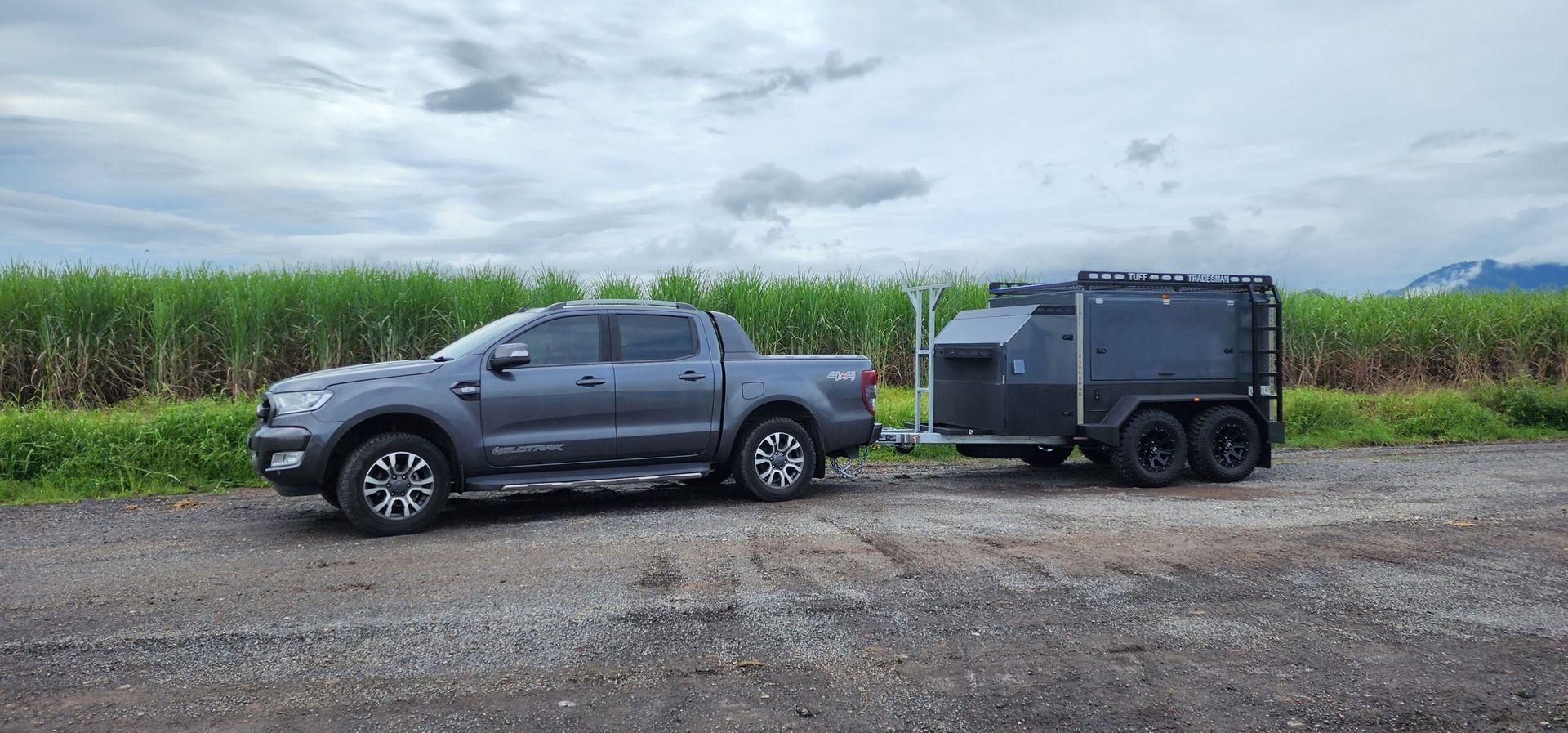 A truck is towing a trailer in a dirt field.