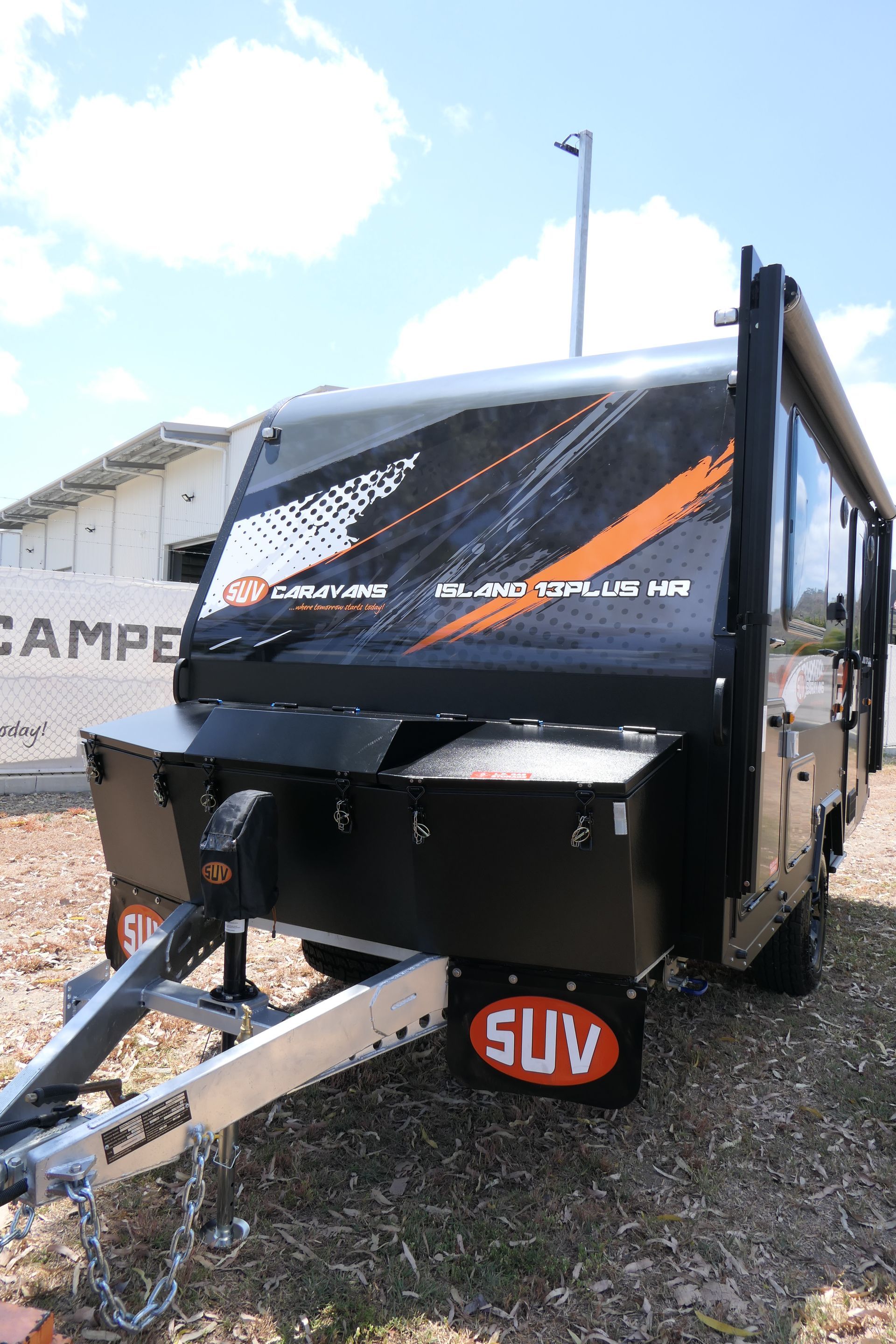 A black and orange suv trailer is parked in a field.