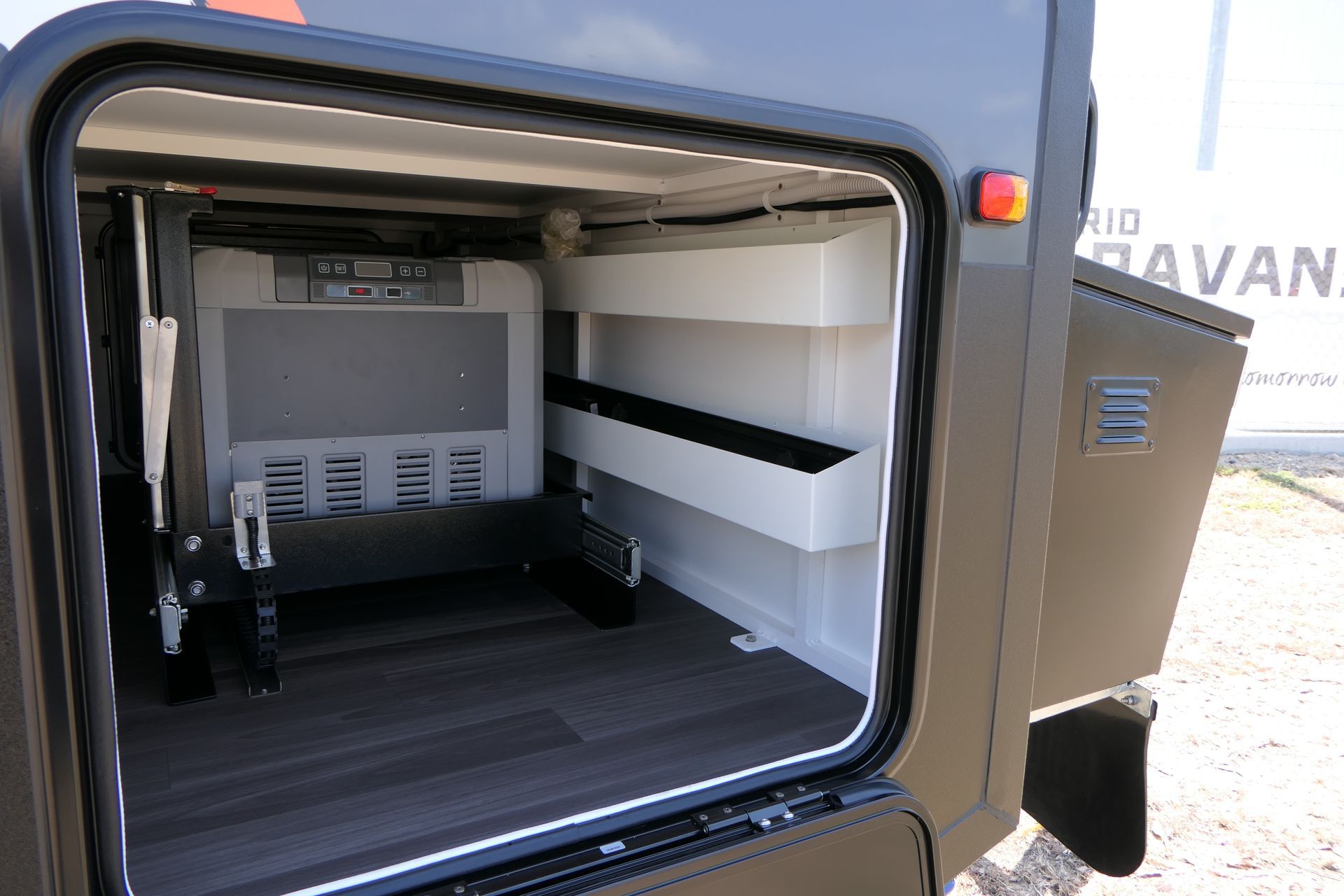 The back of a camper with a refrigerator and shelves.