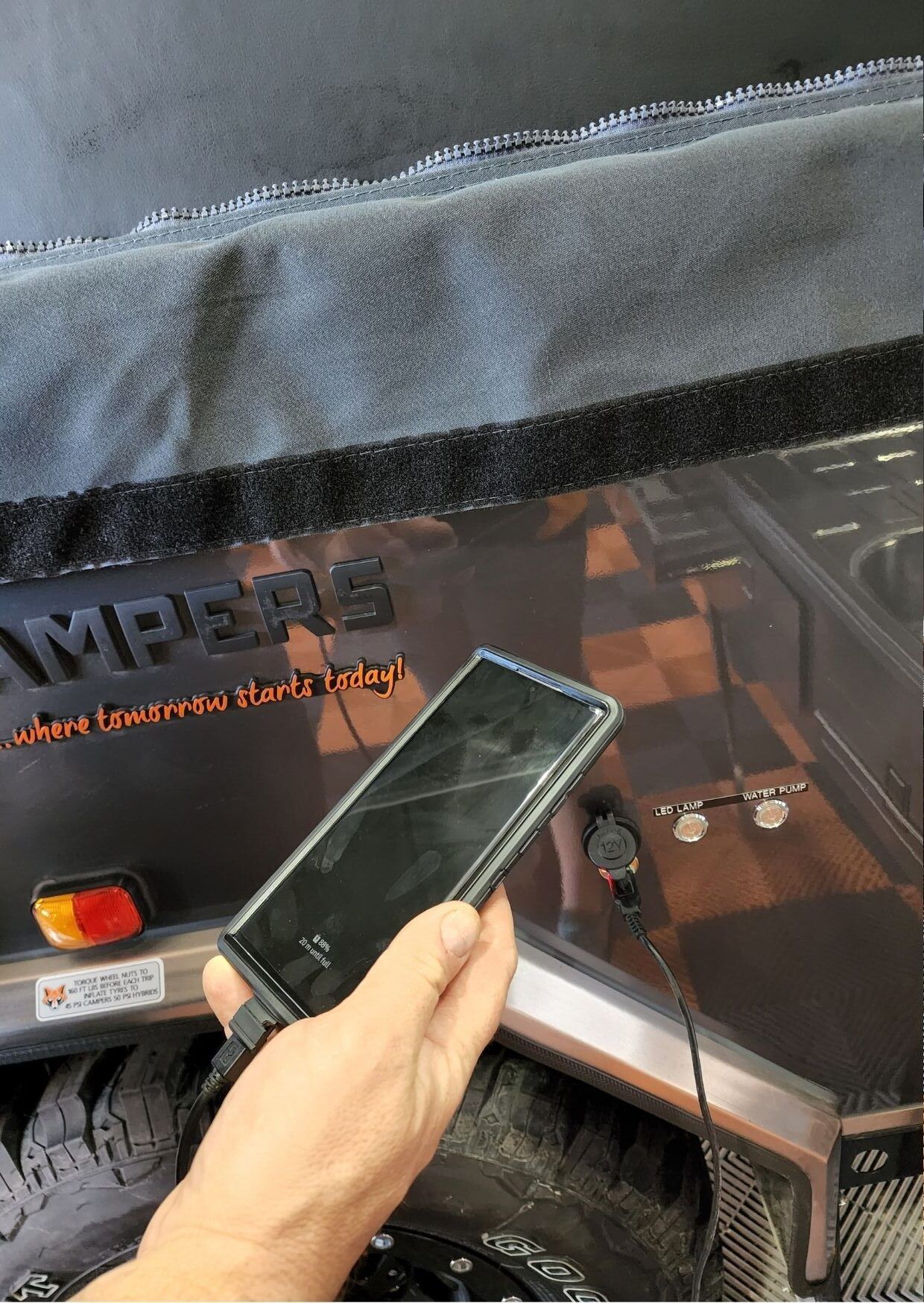 A person is holding a cell phone in front of a jeep