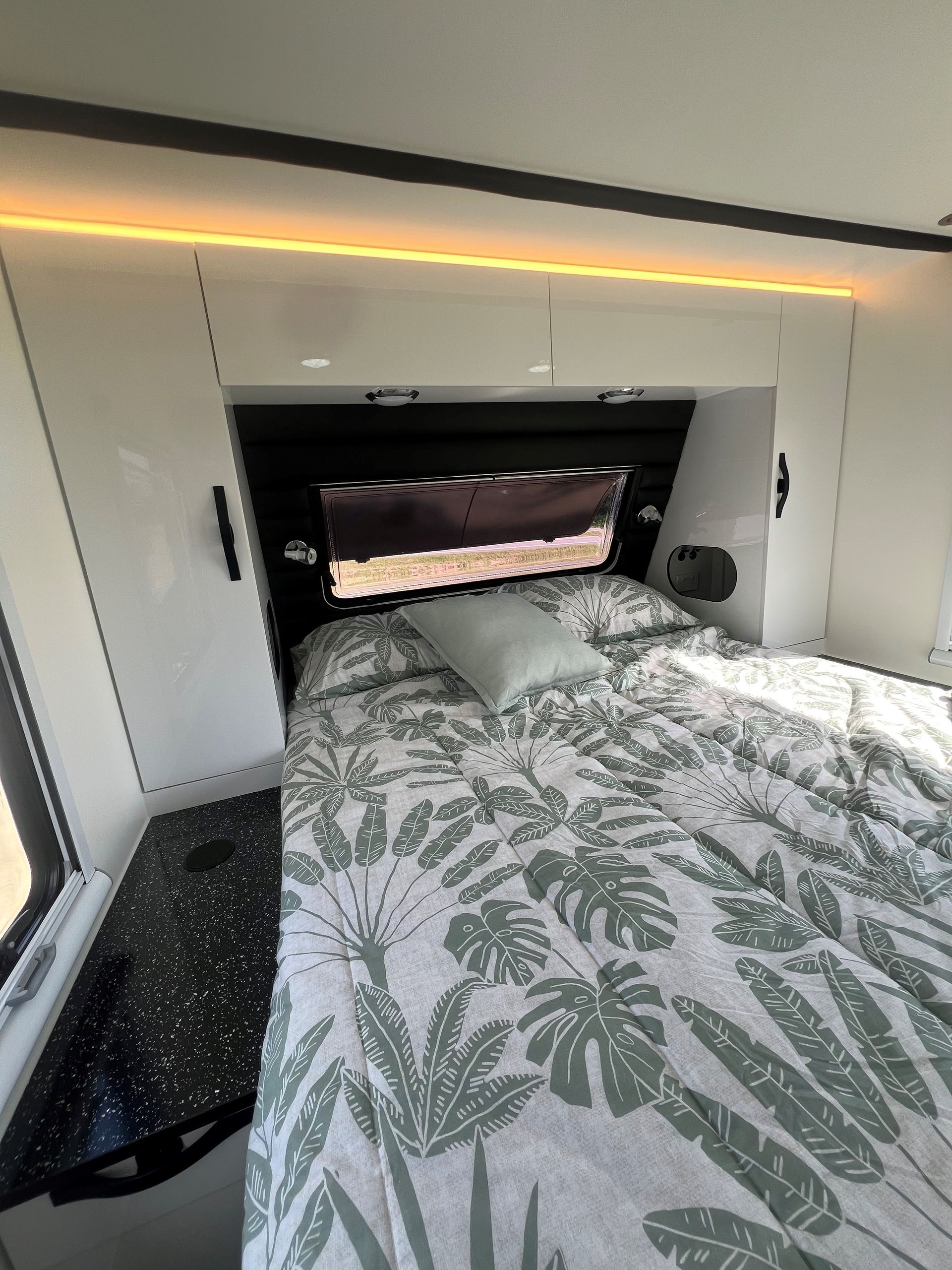 A bedroom in a camper with a bed and a window.