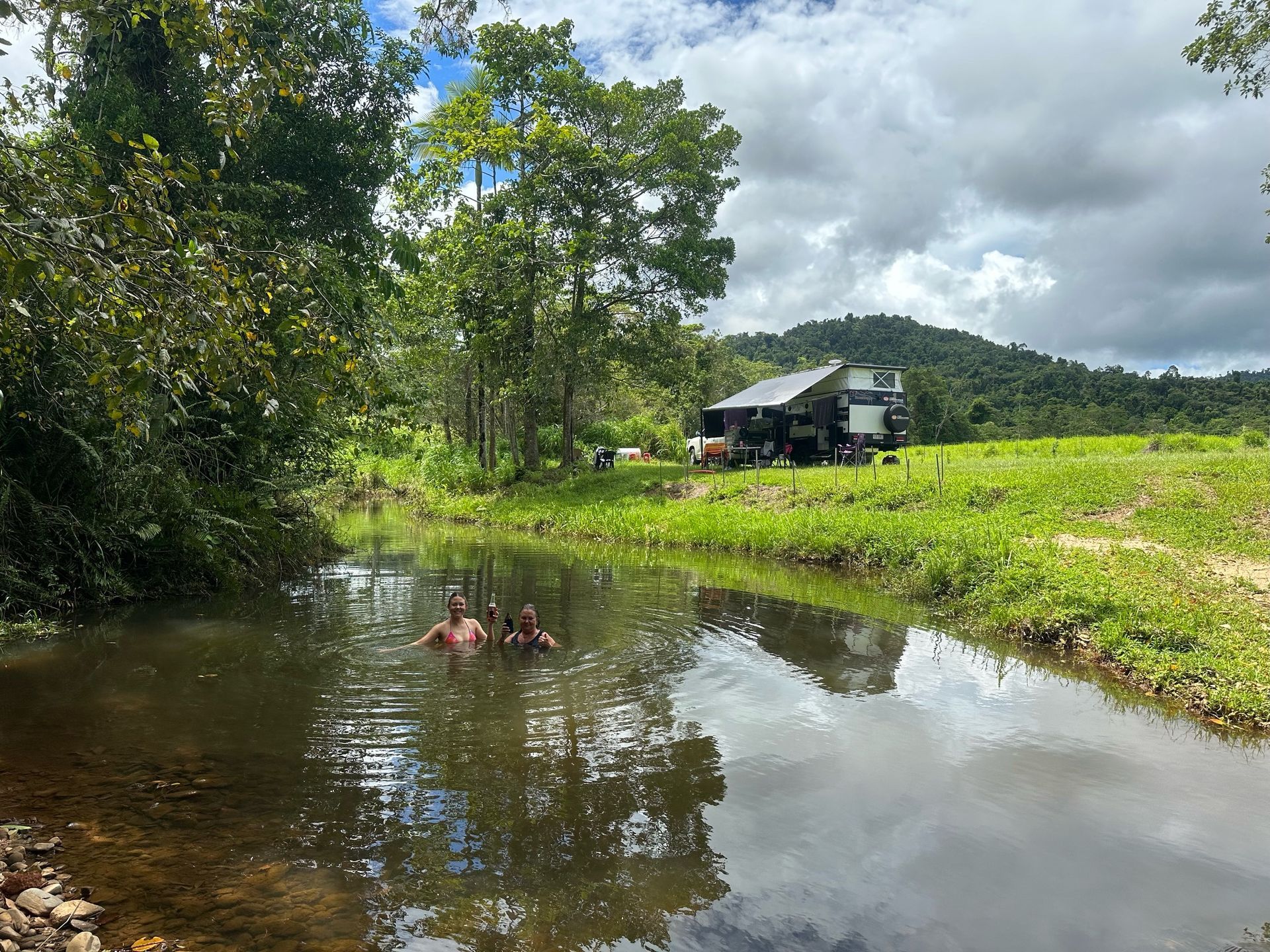 A couple of people are swimming in a small river.