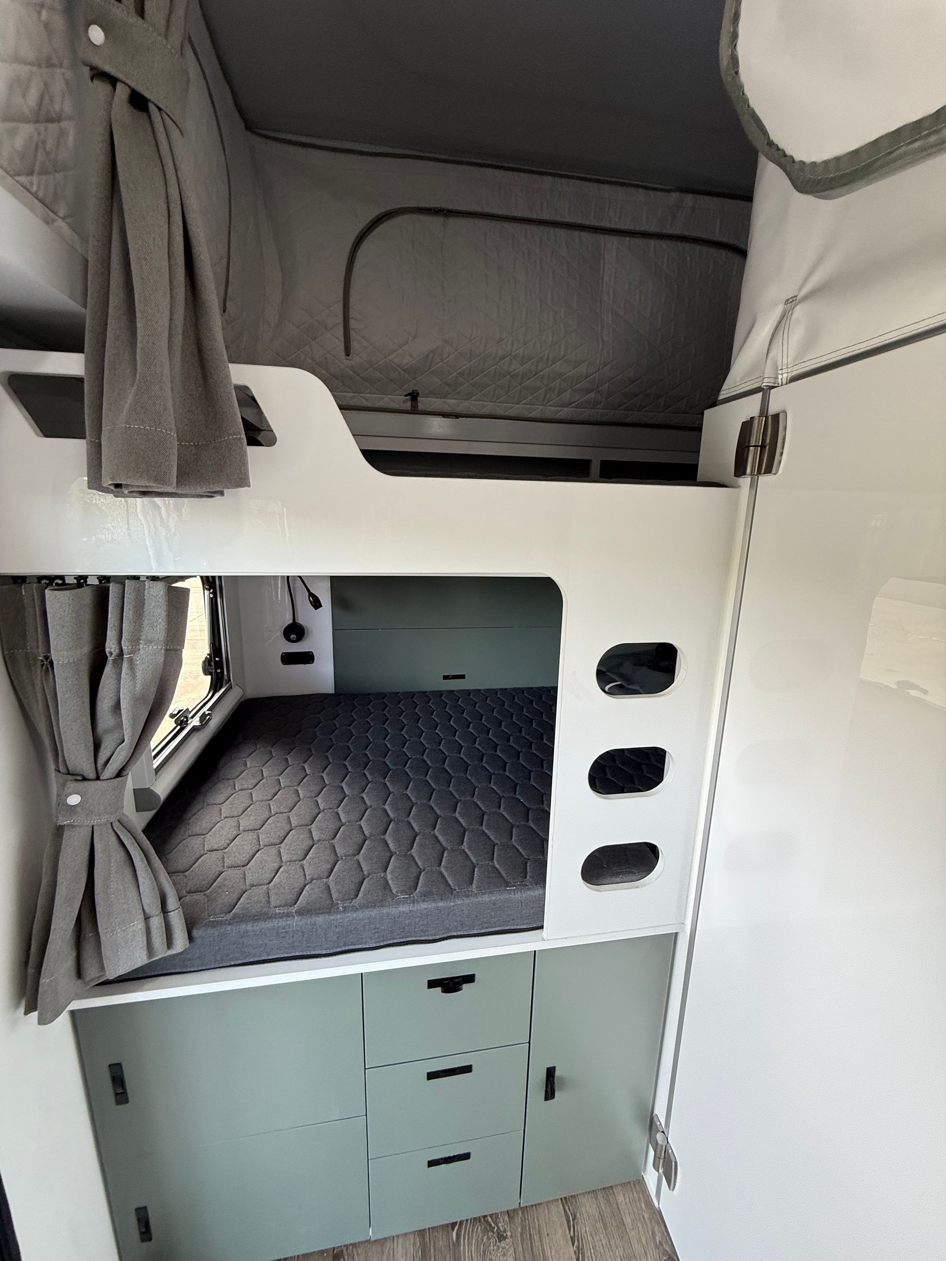 The inside of a camper with a bunk bed and a window.