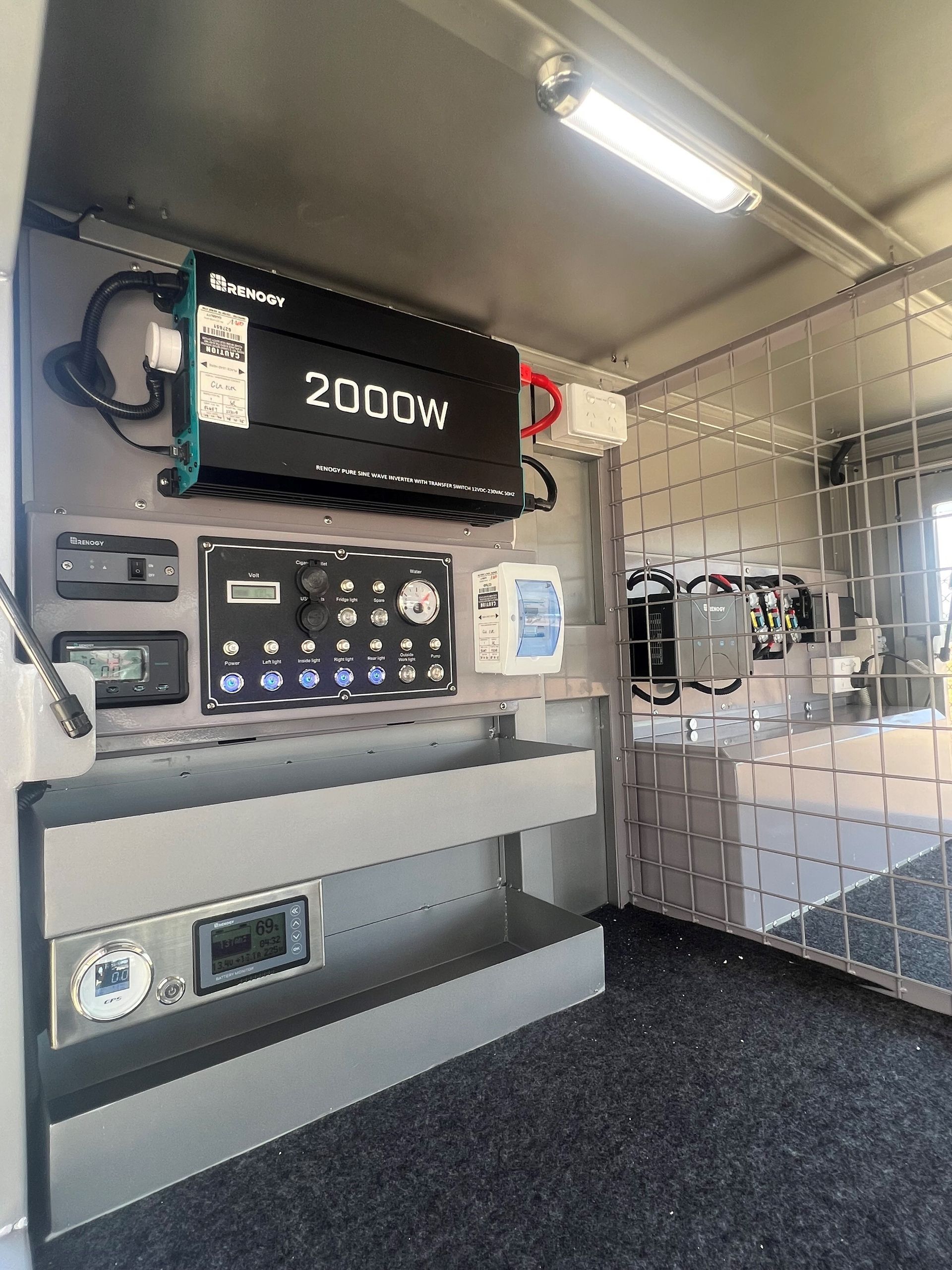 The inside of a van with a 2000w inverter on the wall.