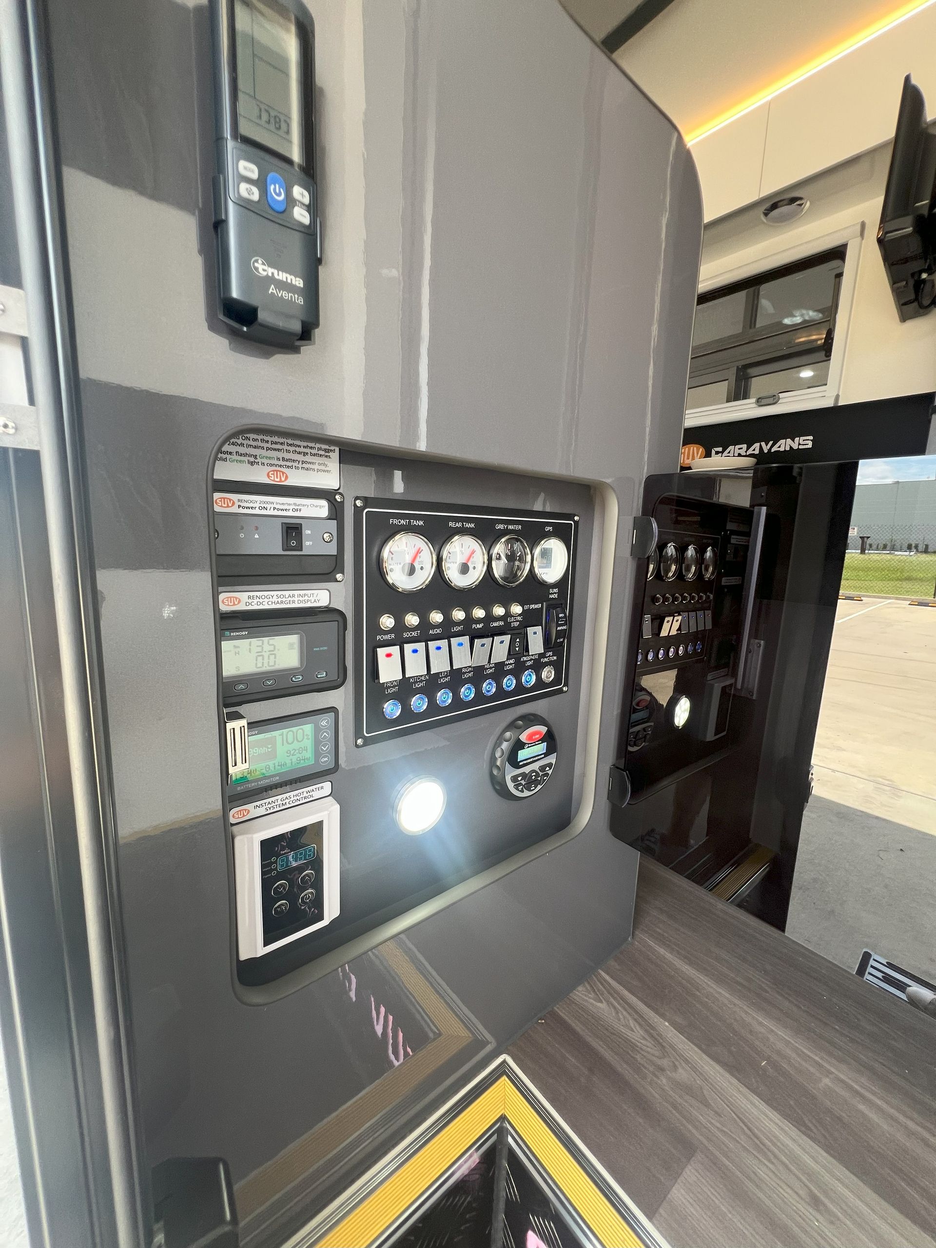 Control panel with switches, gauges, and displays in a vehicle. Gray and black with interior lighting.