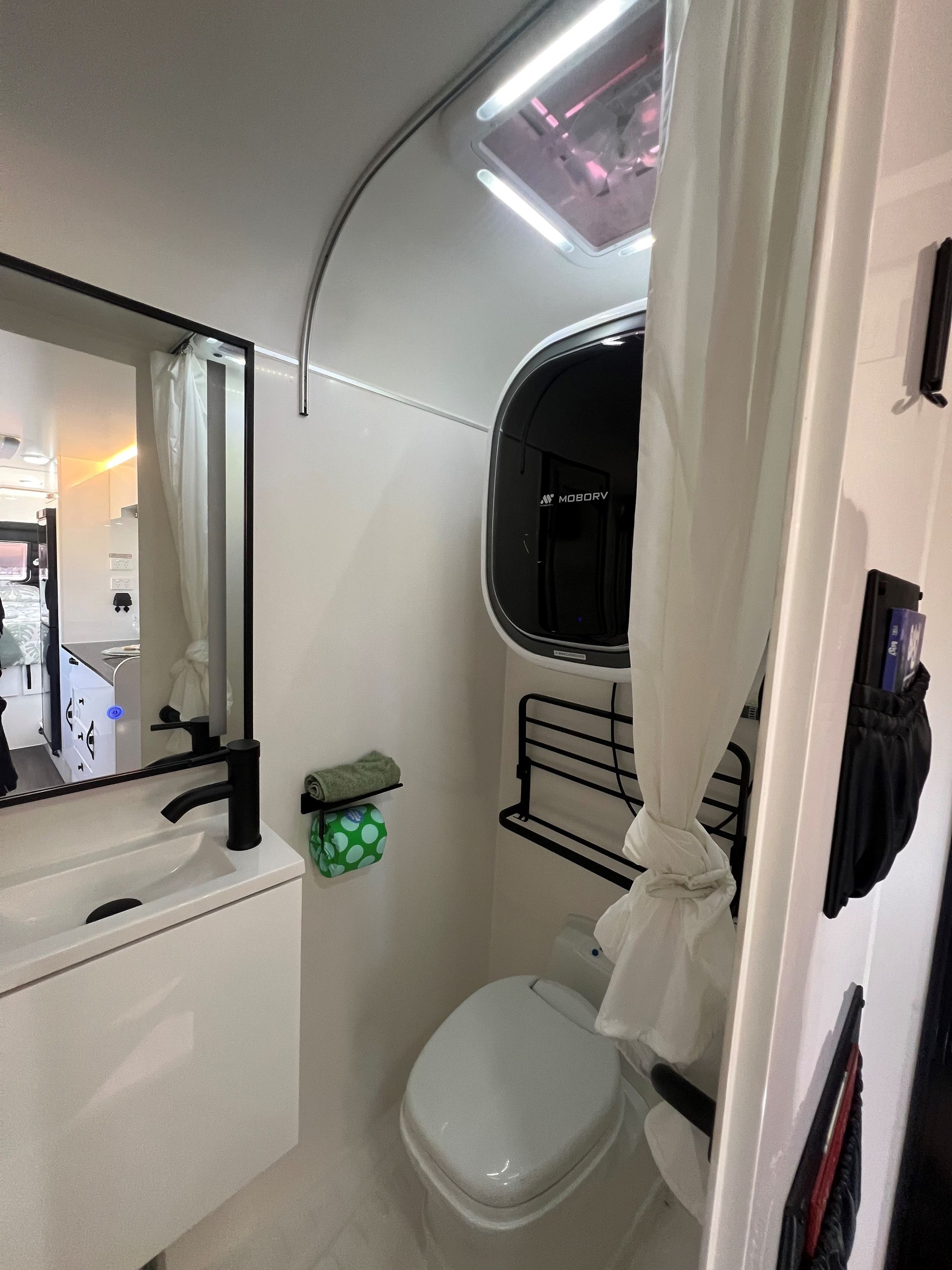 A bathroom with a toilet , sink and mirror.
