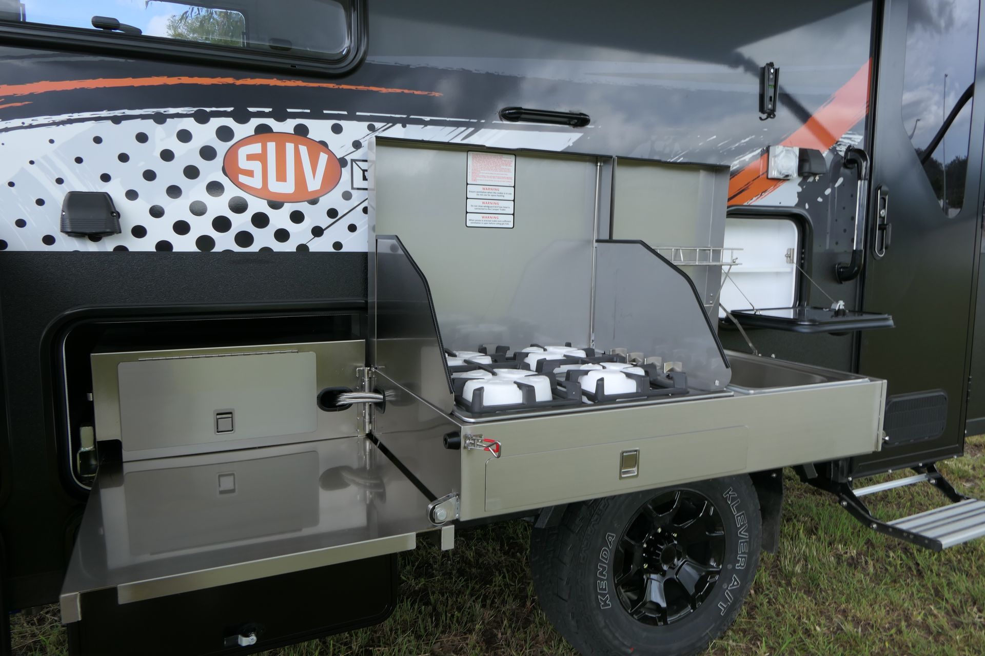 A campsite cooking station extending from the side of an SUV camper.