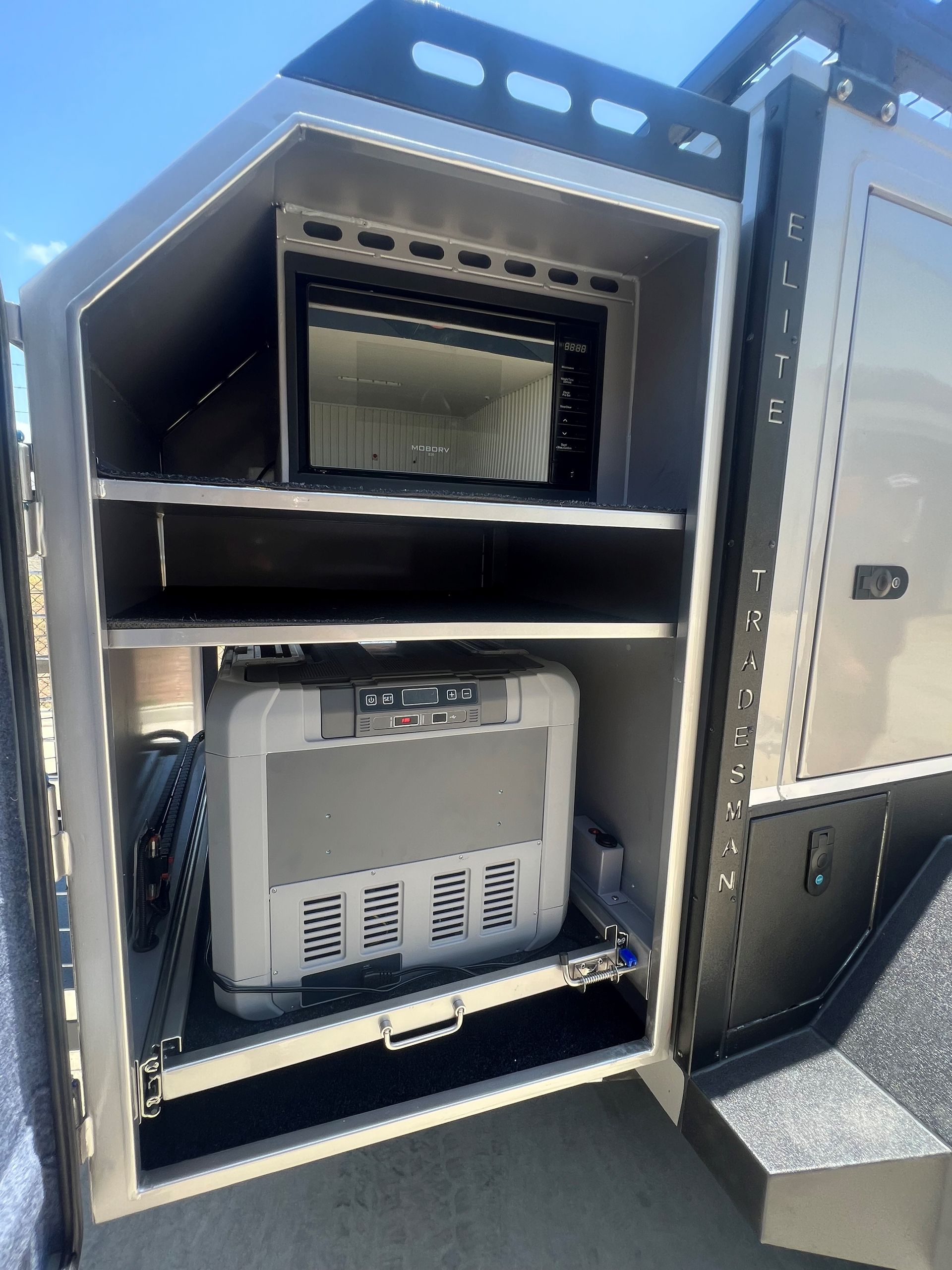 A stainless steel box with a microwave inside of it.