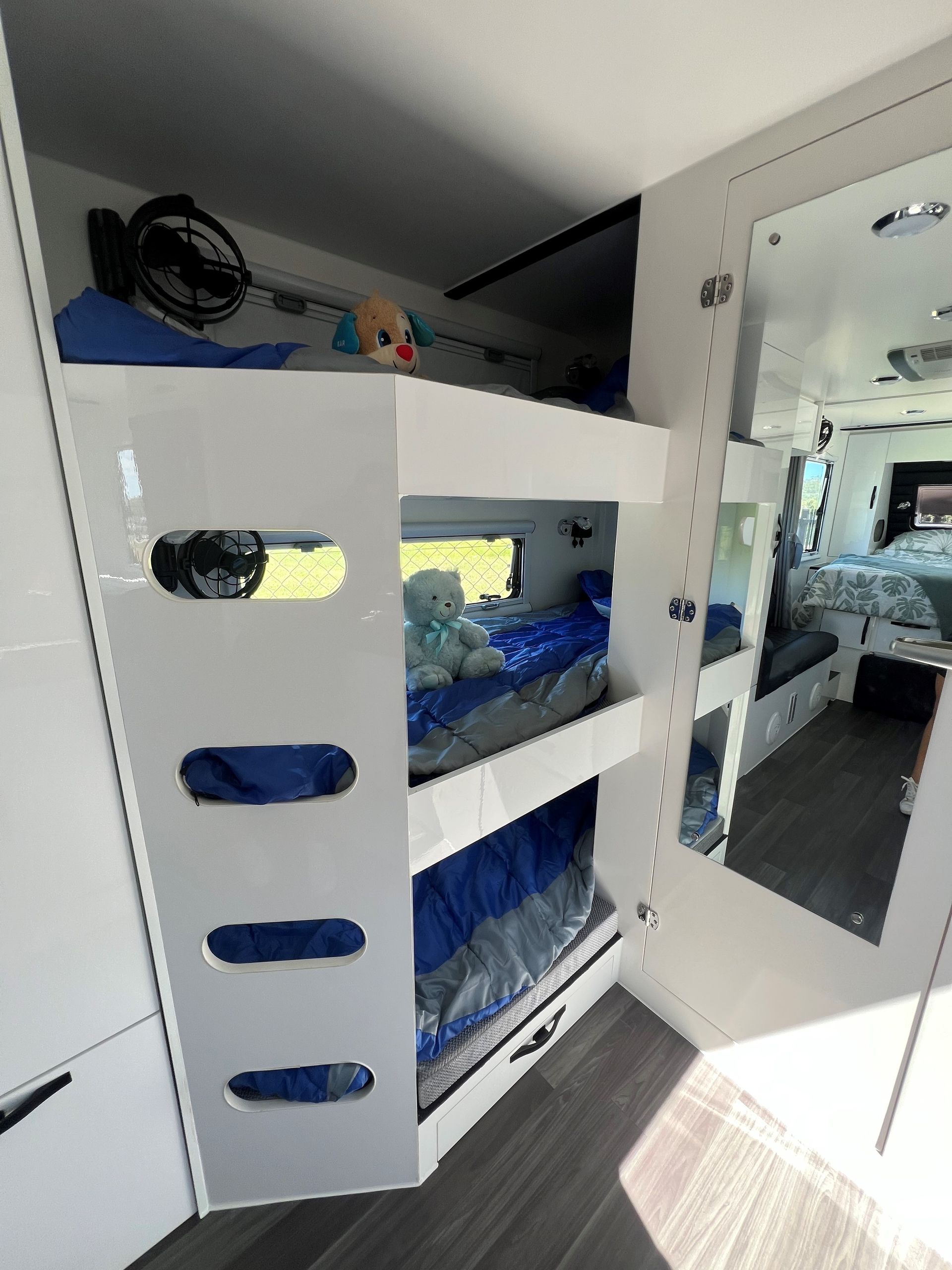 A bunk bed in a camper with a mirror and a fan.