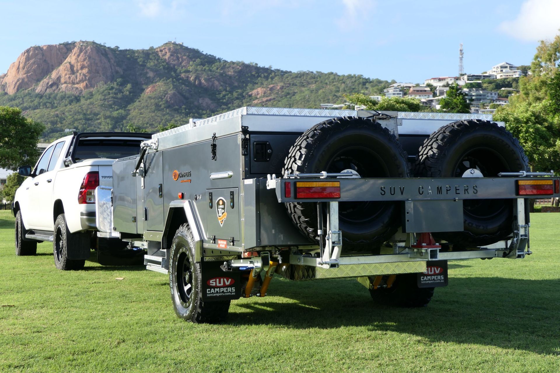 A white truck is pulling a trailer with a mountain in the background