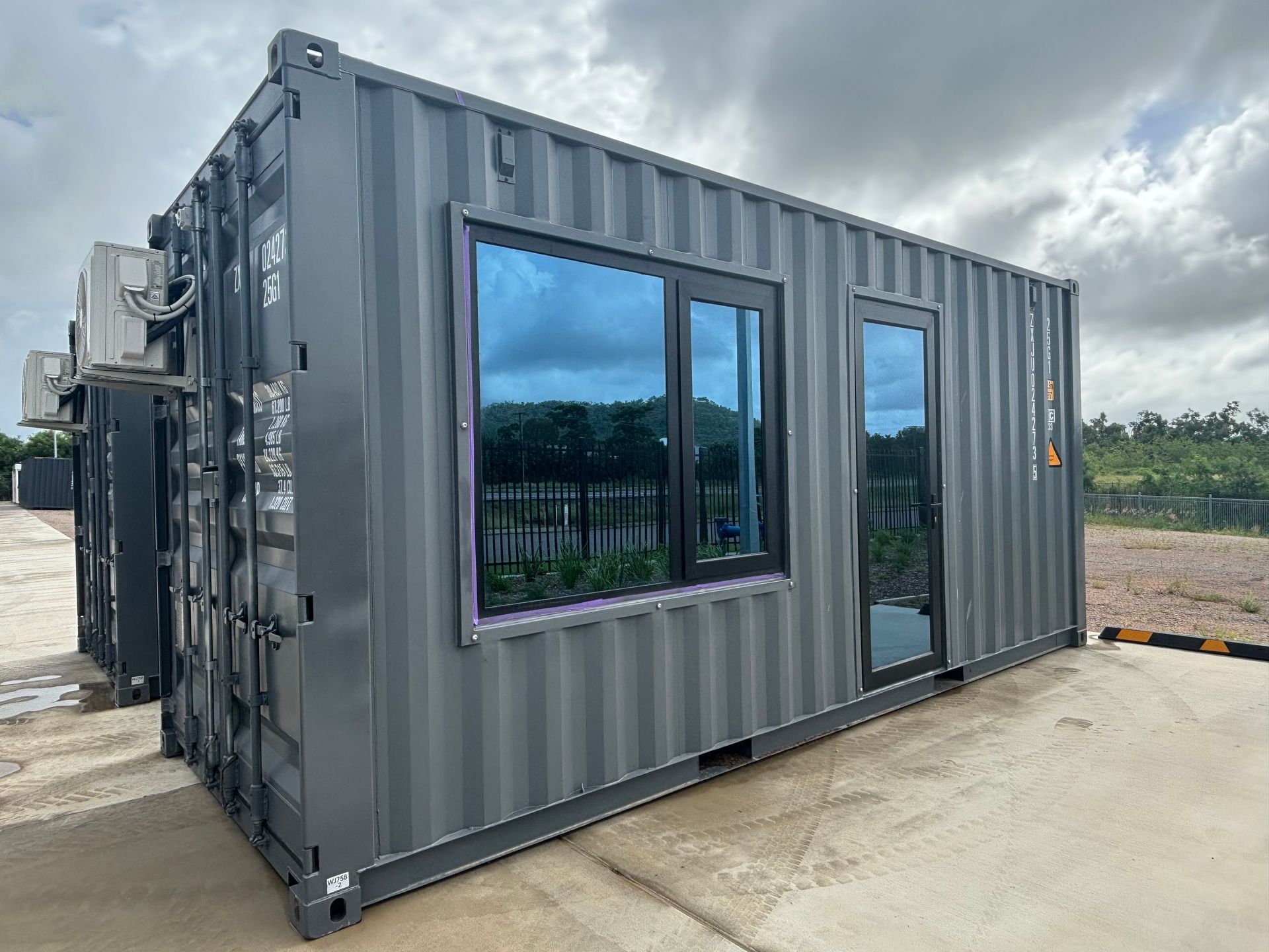 A container house with two windows and a sliding glass door.