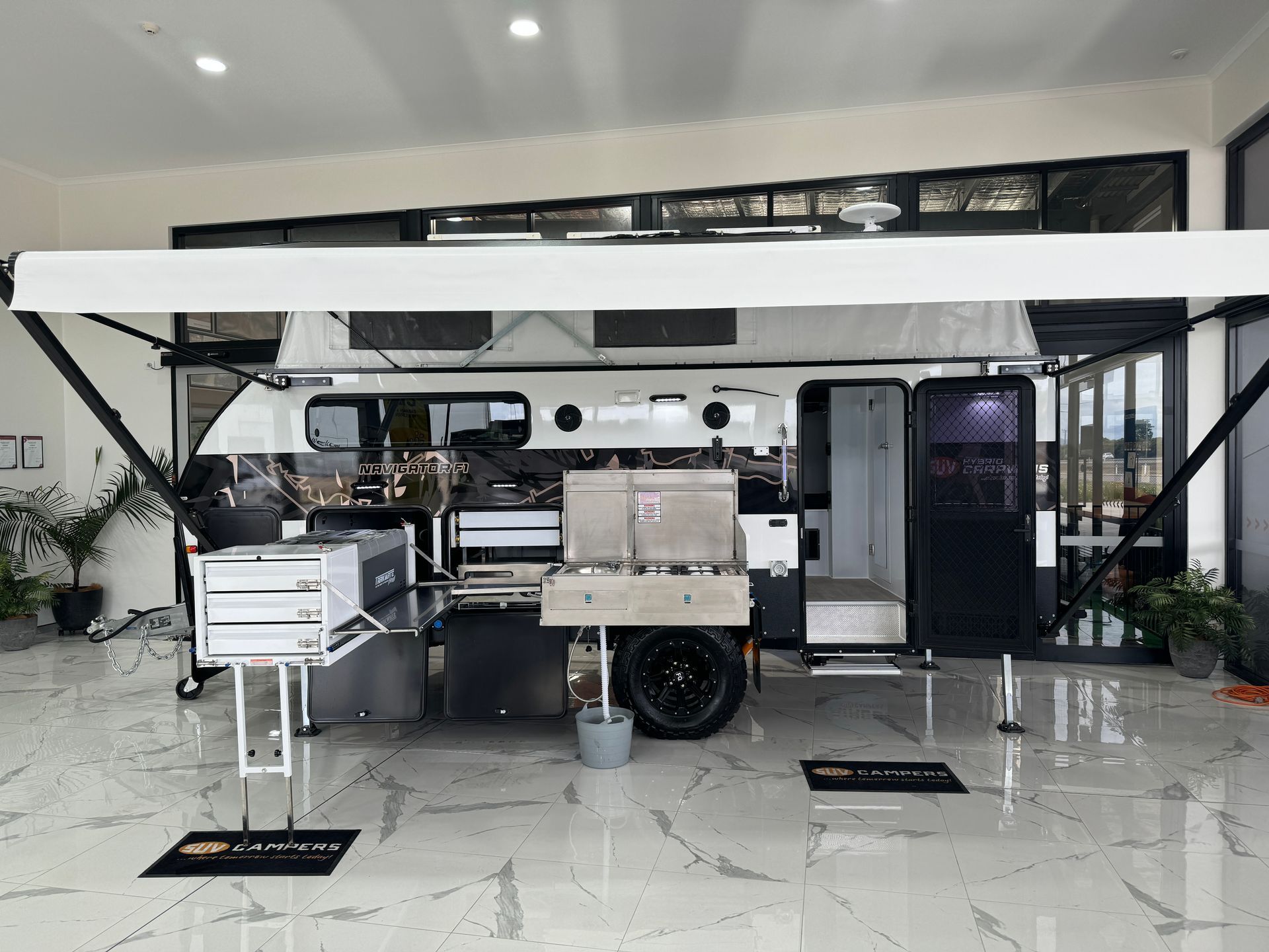 A trailer with a white awning is parked in a room.