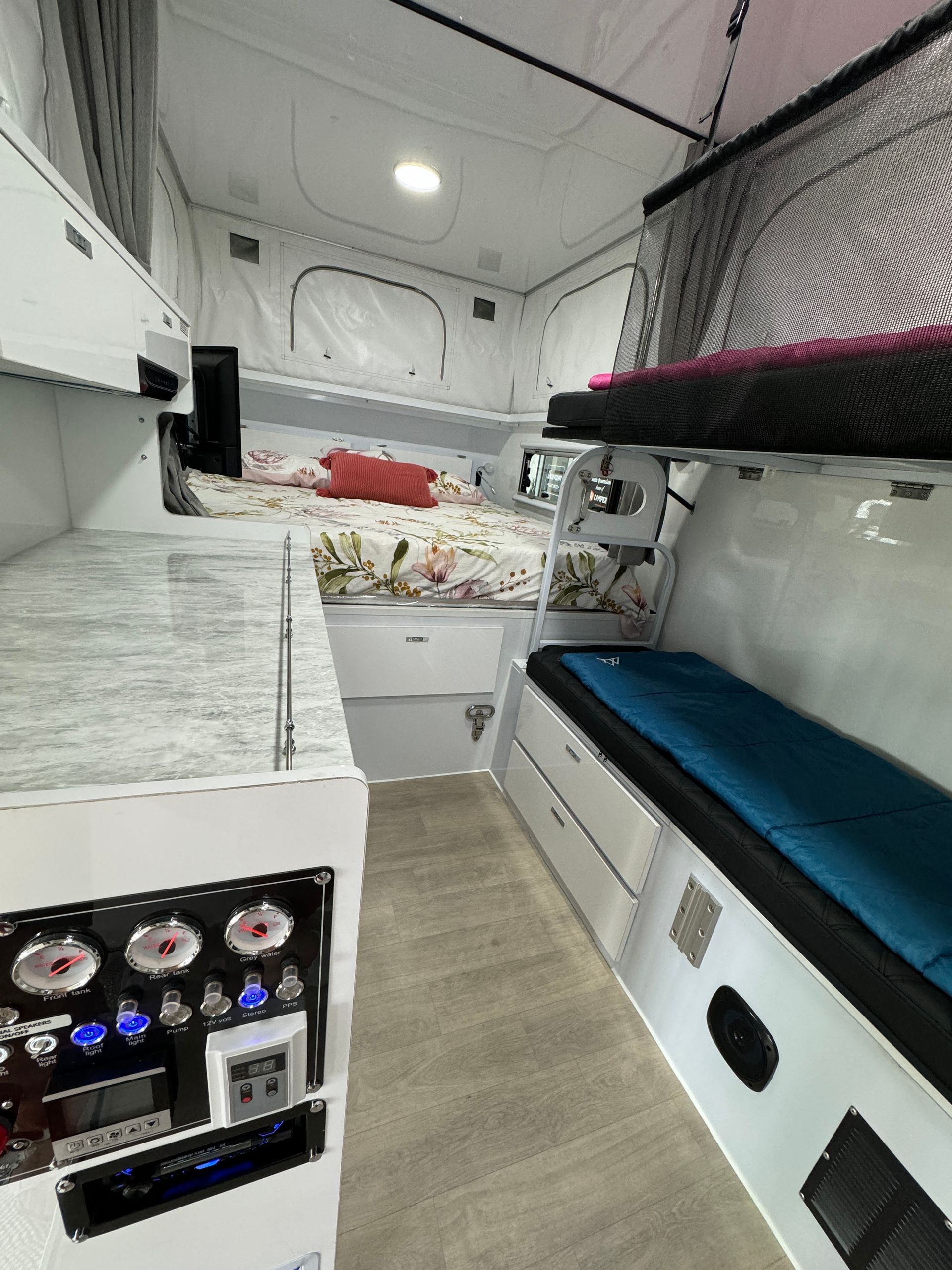 The inside of a camper with a bed and bunk beds.