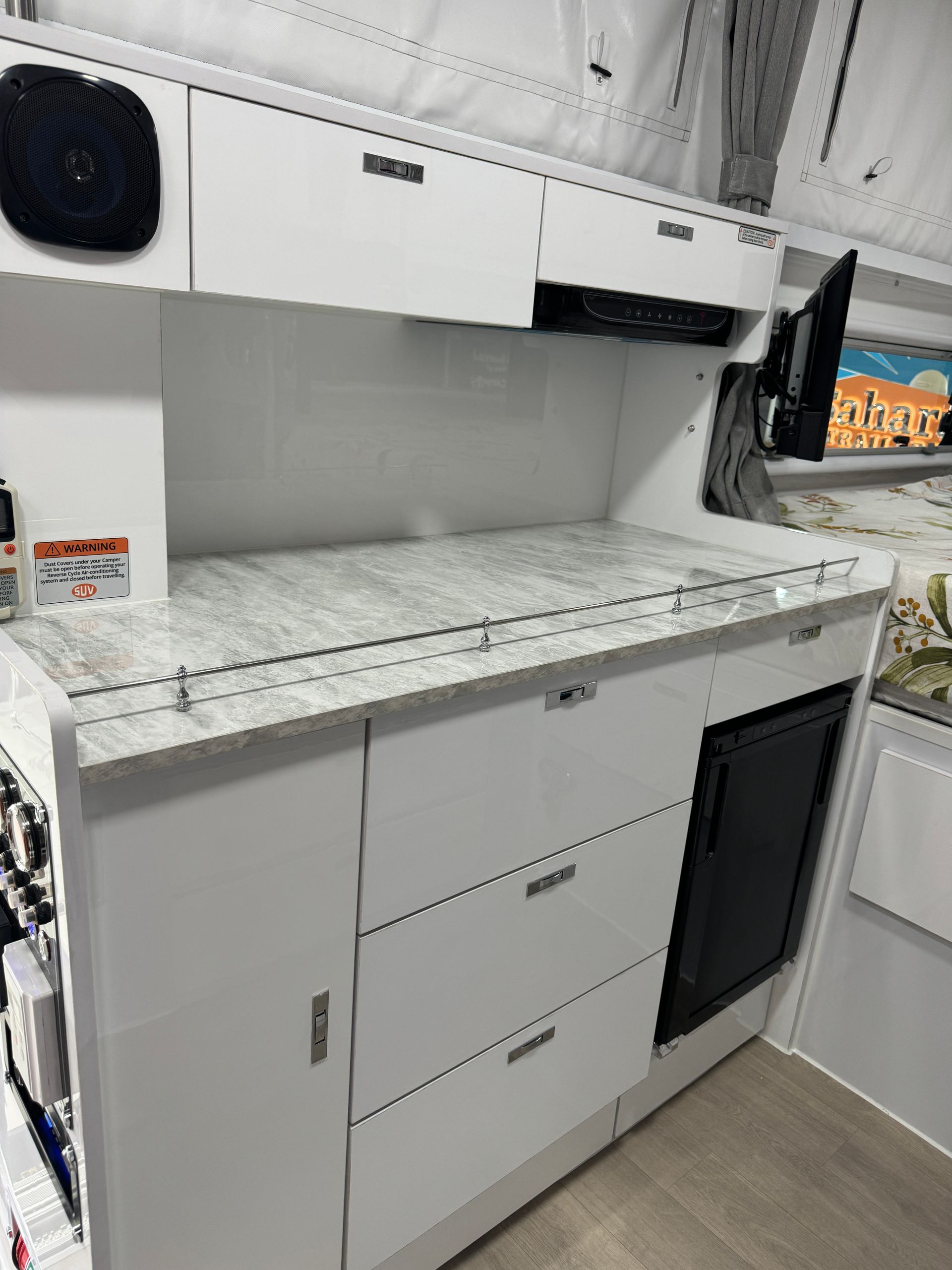 A kitchen with white cabinets , drawers , and a refrigerator.