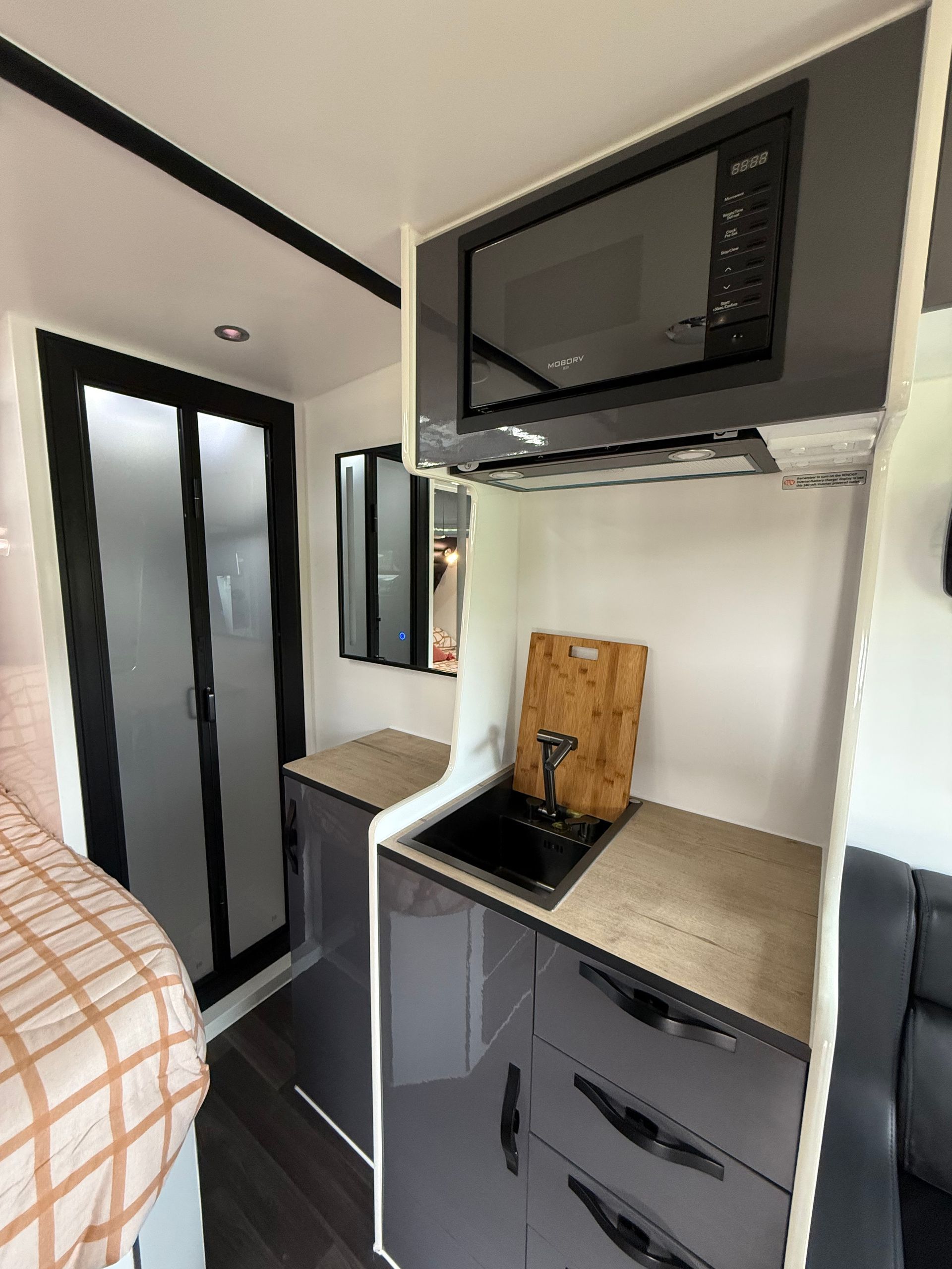 A kitchen with a sink , microwave , and mirror.