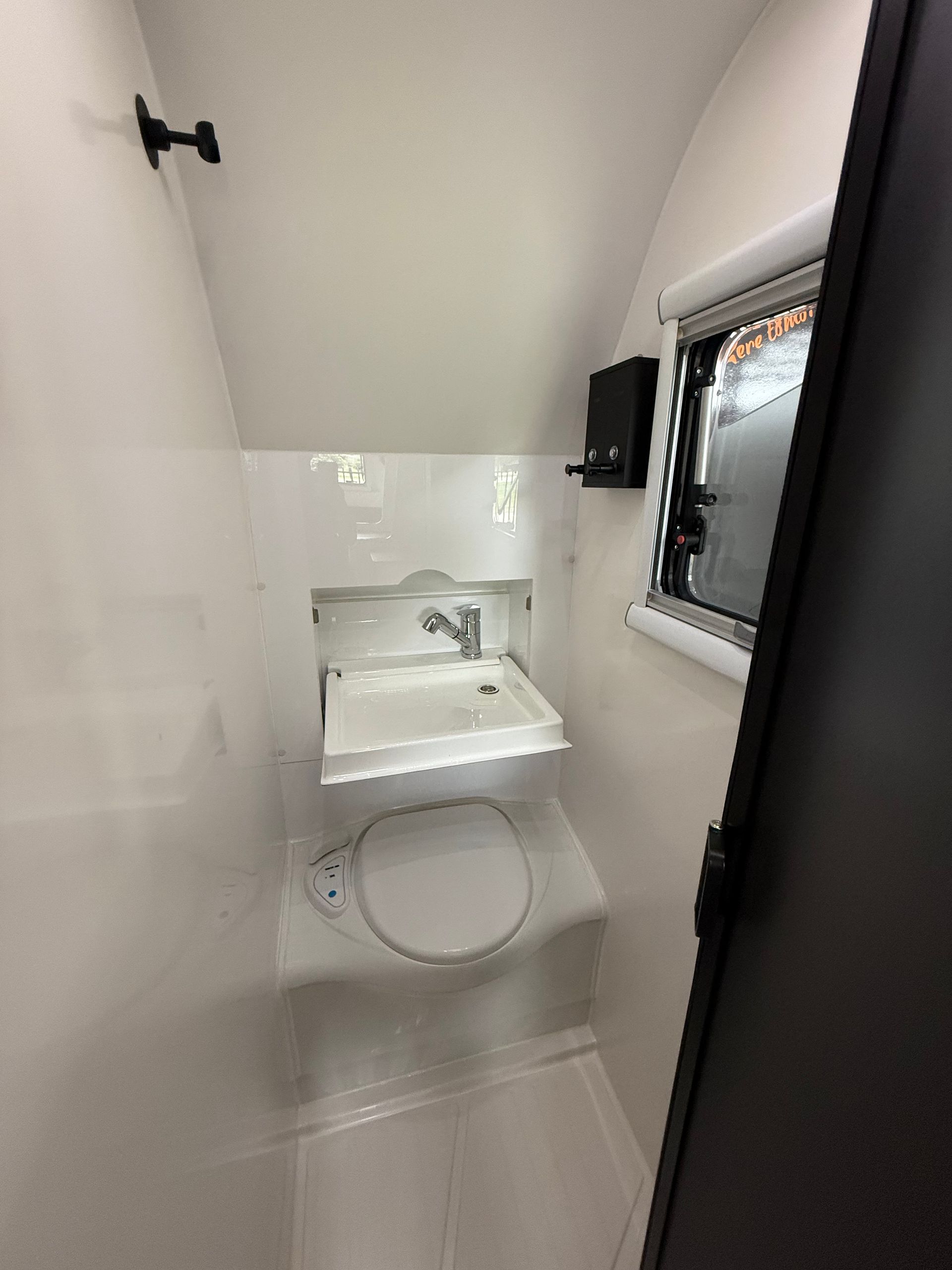 A bathroom with a toilet , sink and window.