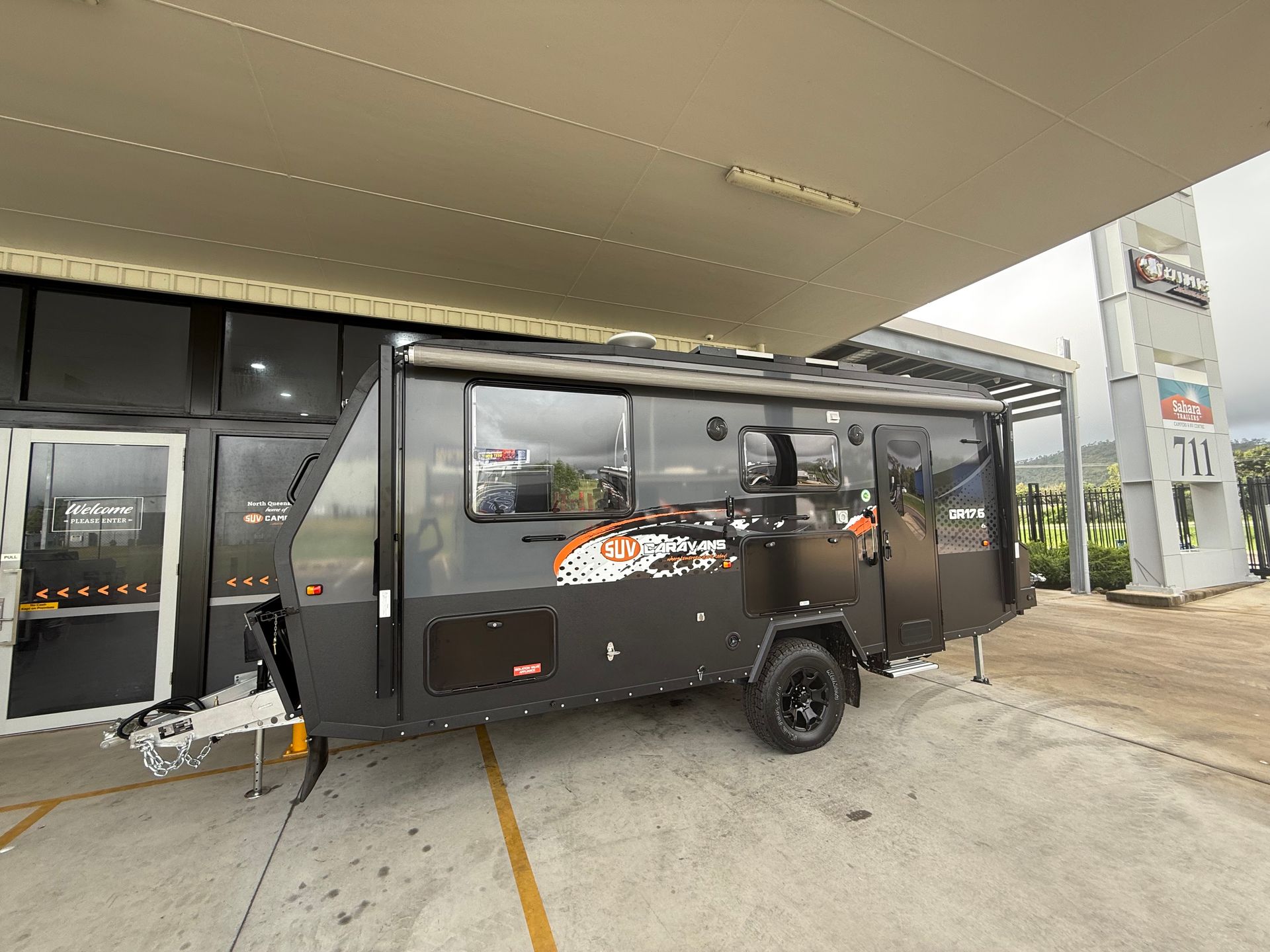 A black trailer is parked in front of a building.