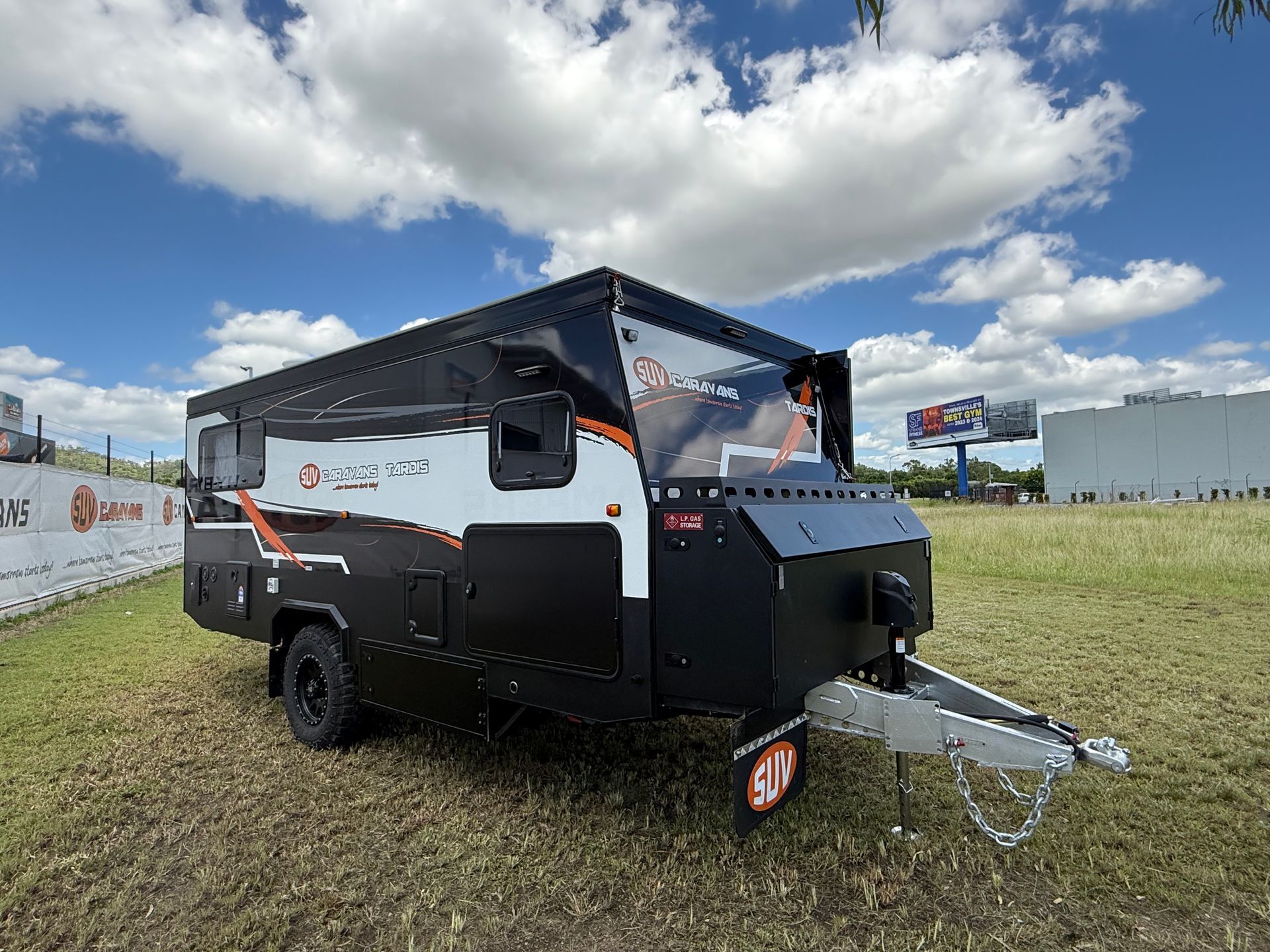 A black and white trailer is parked in a grassy field.