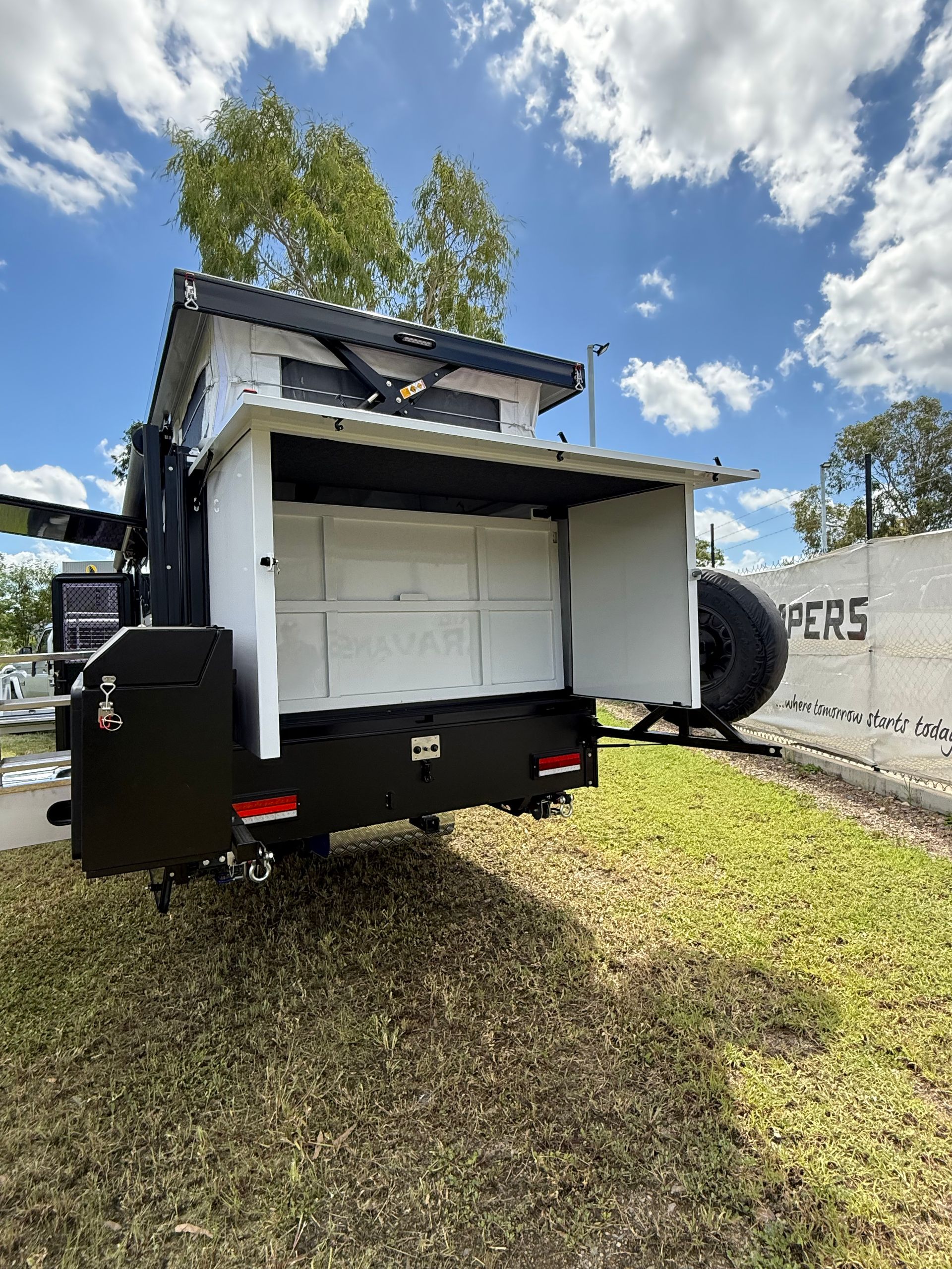 A trailer is parked in a grassy field with its doors open.
