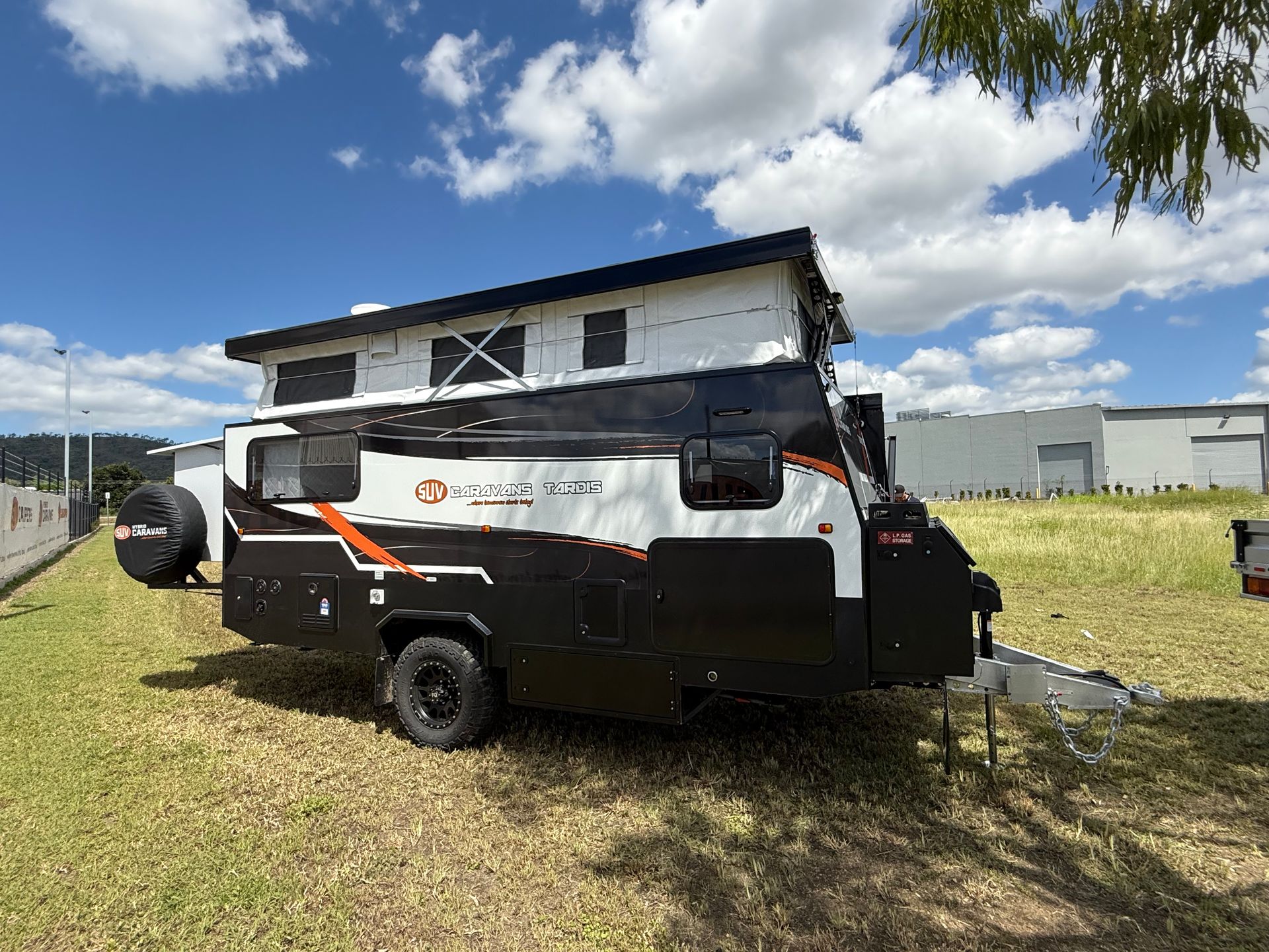 A black and white camper trailer is parked in a grassy field.