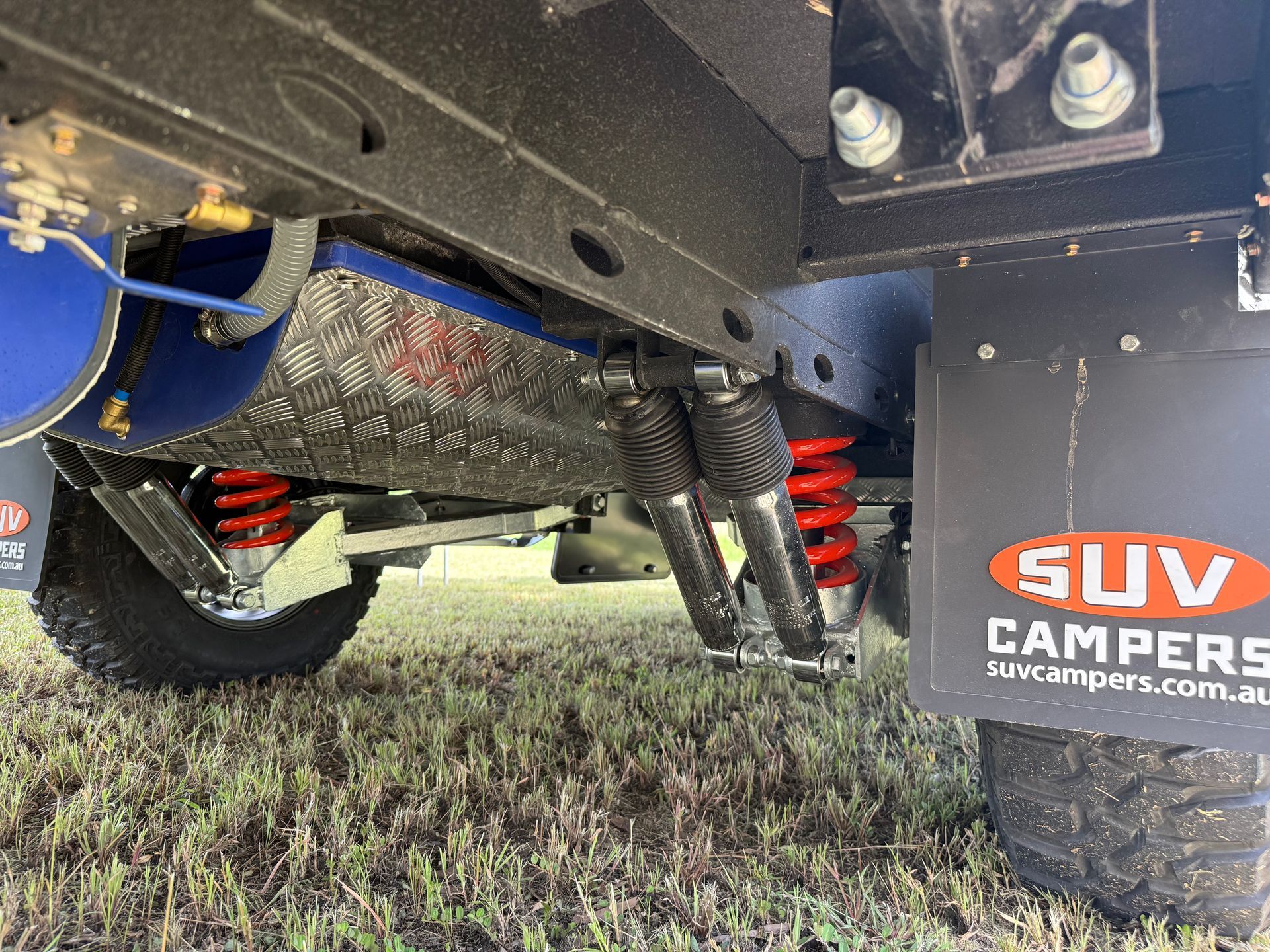 A close up of the underside of a suv parked in the grass.
