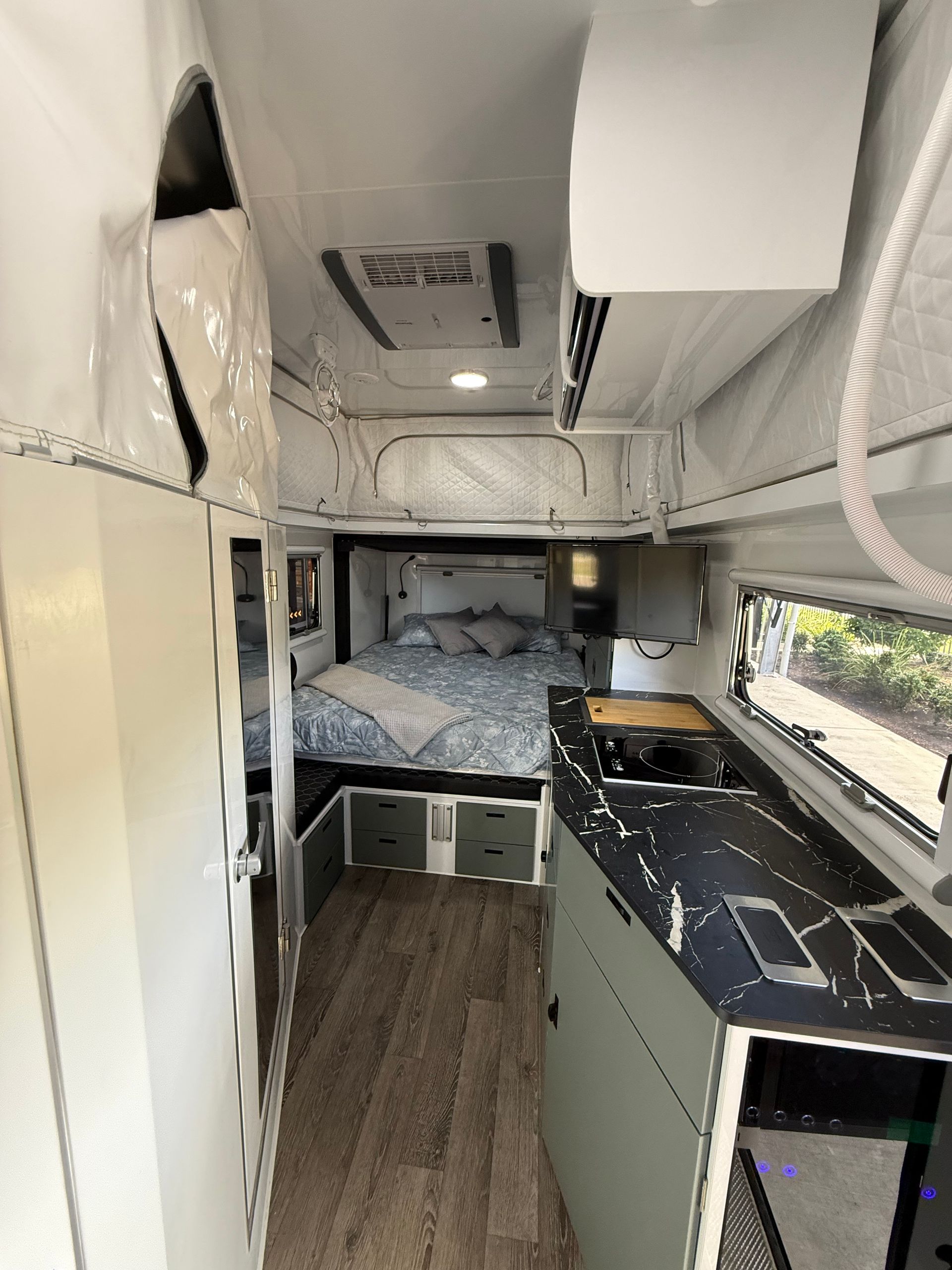 The inside of a camper with a bed and a kitchen.