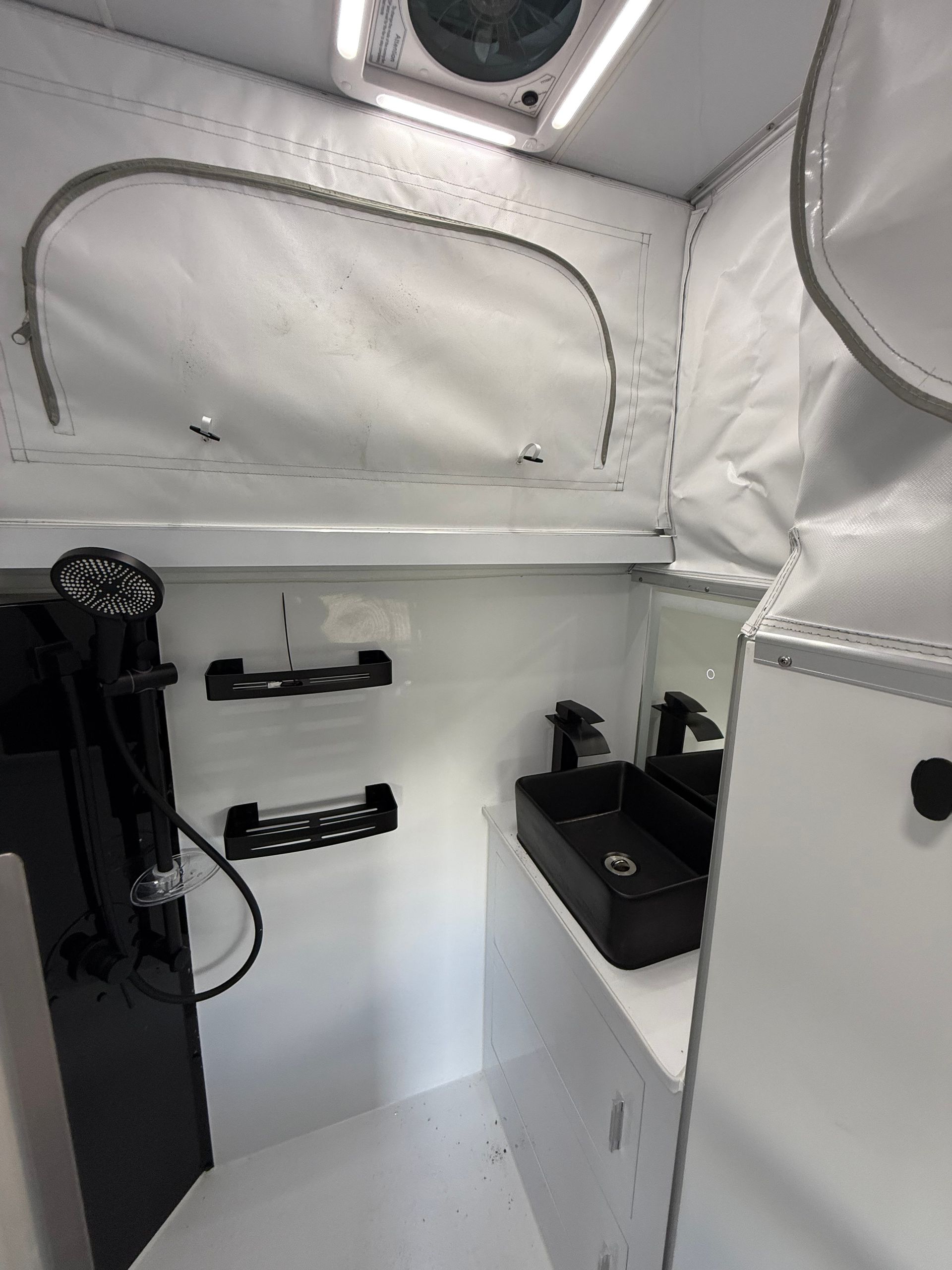 A bathroom in a camper van with a sink and a shower.