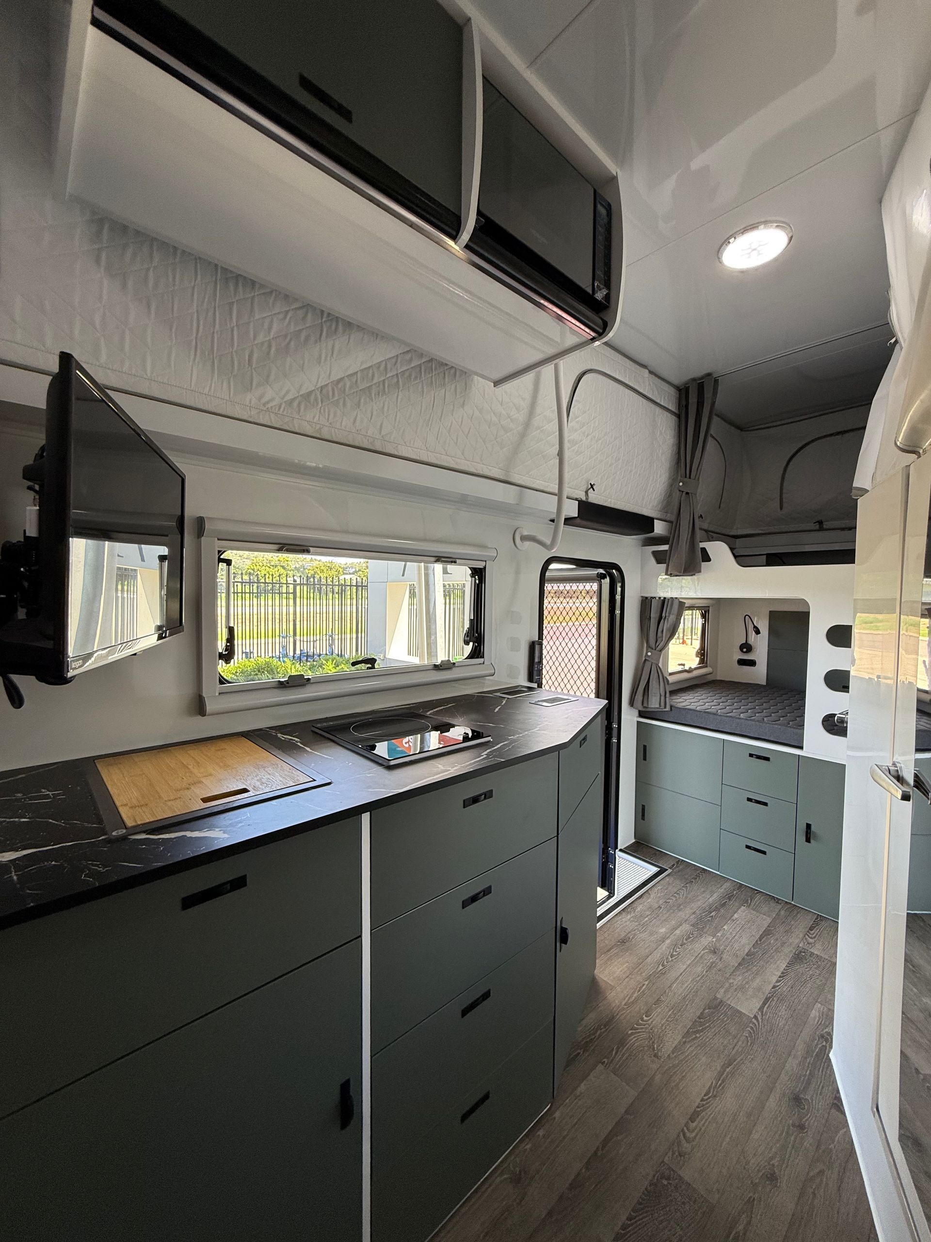 A kitchen in a camper with a tv on the wall.