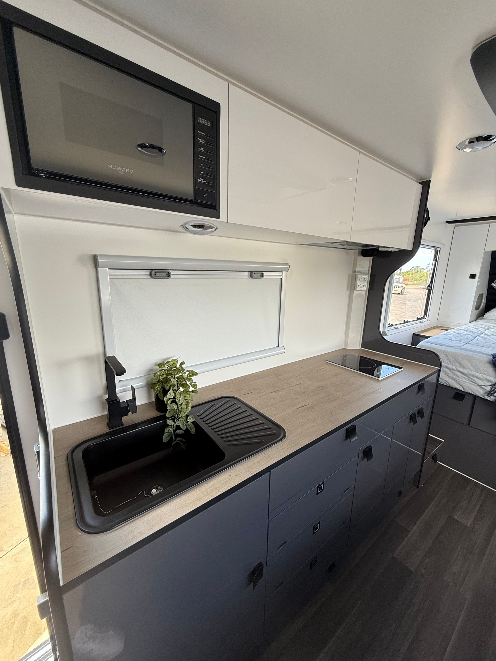 A kitchen in a camper van with a sink , microwave , and stove.