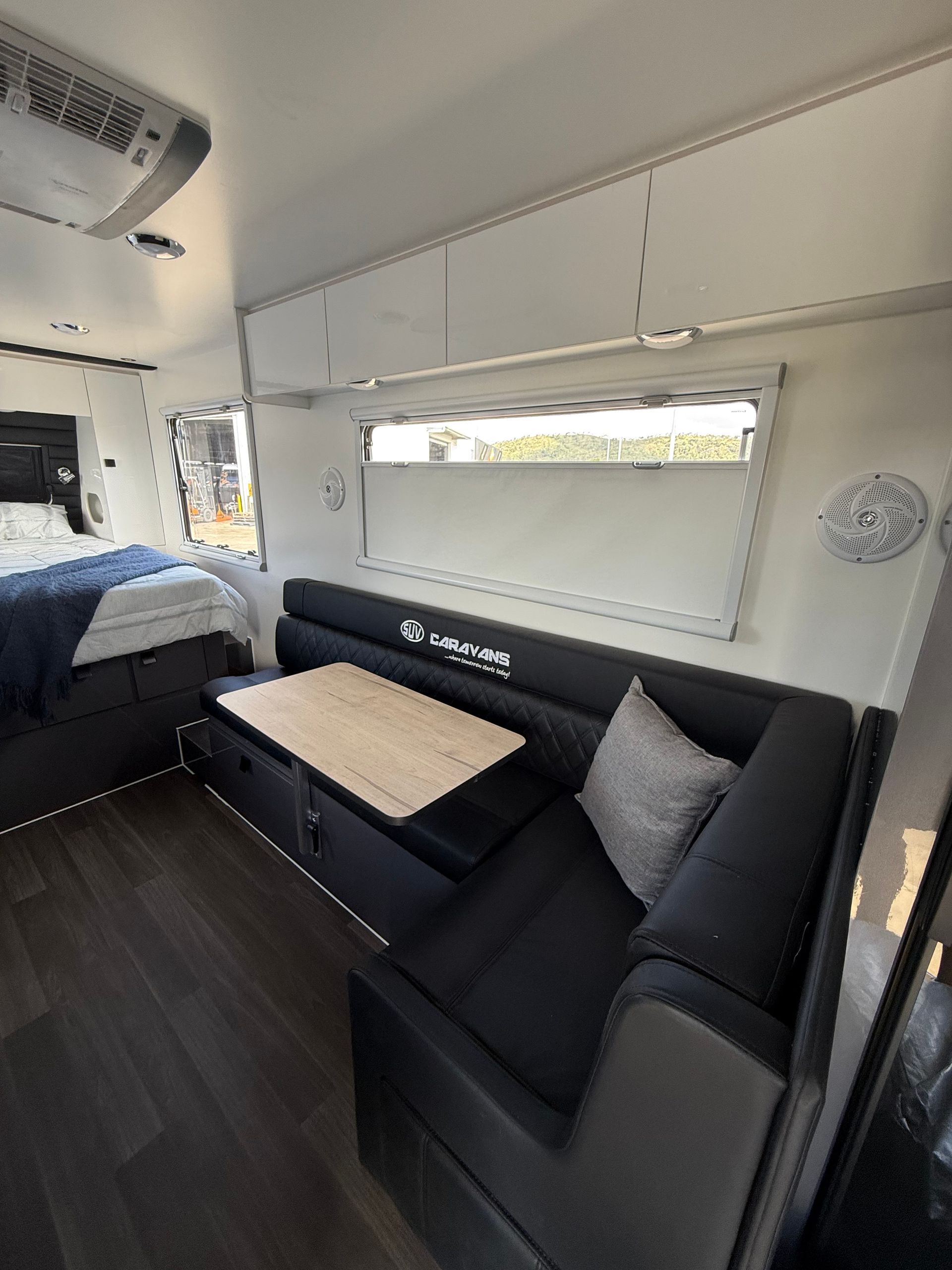 A living room in a camper with a couch , table and bed.