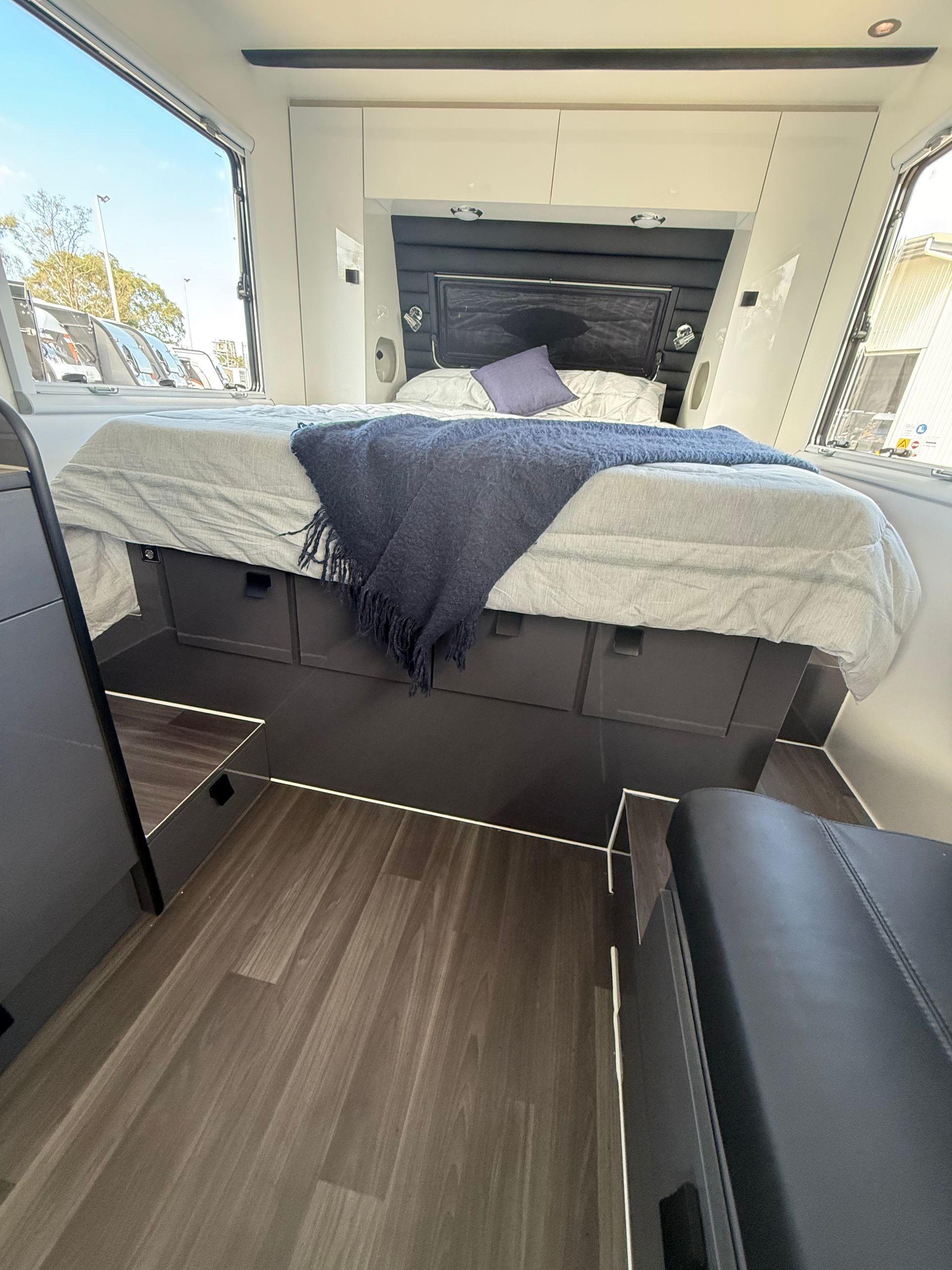 A bed with a blue blanket on it is in a camper.