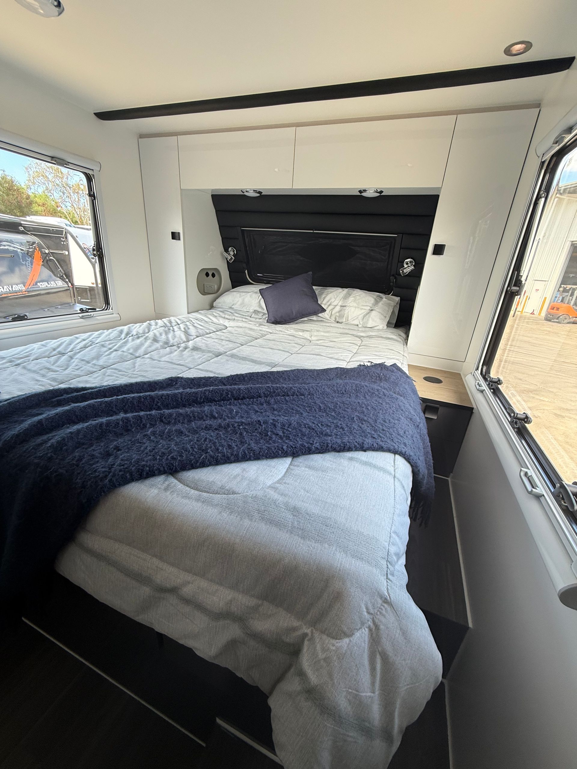 A bedroom in a camper with a bed and a window.
