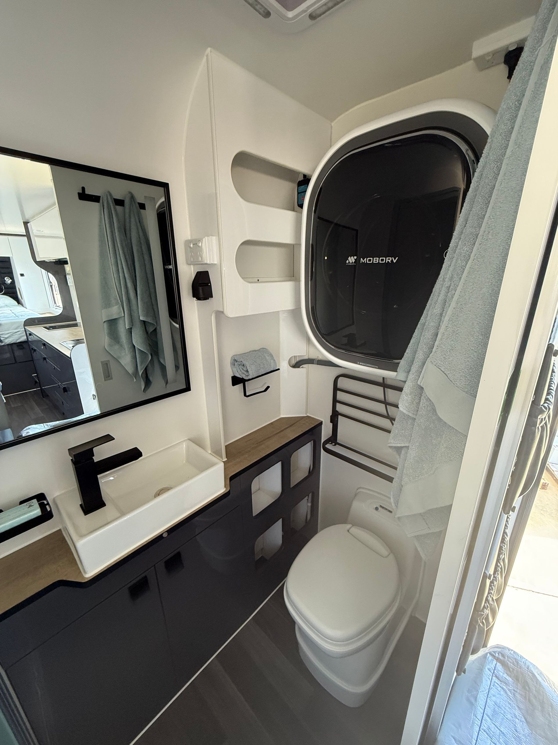 A bathroom with a sink , toilet , shower and mirror.