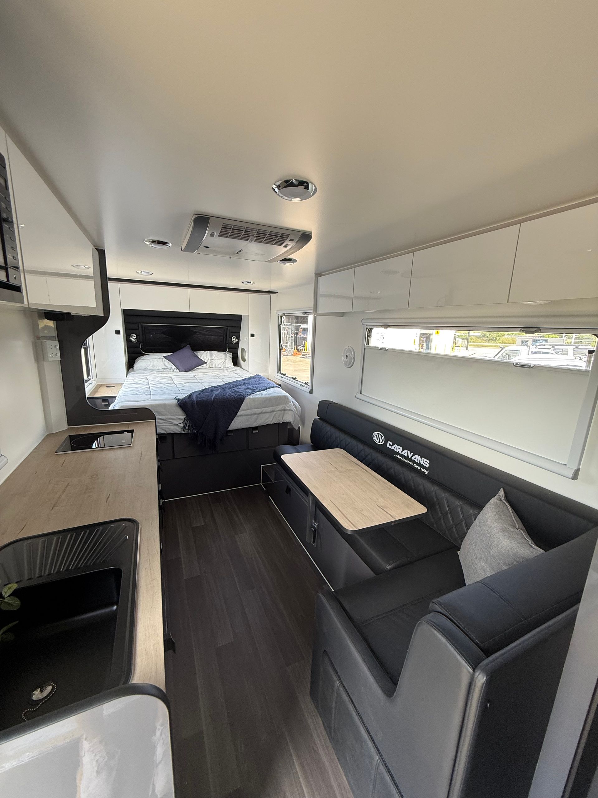 The inside of a camper van with a bed , couch , table and kitchen.