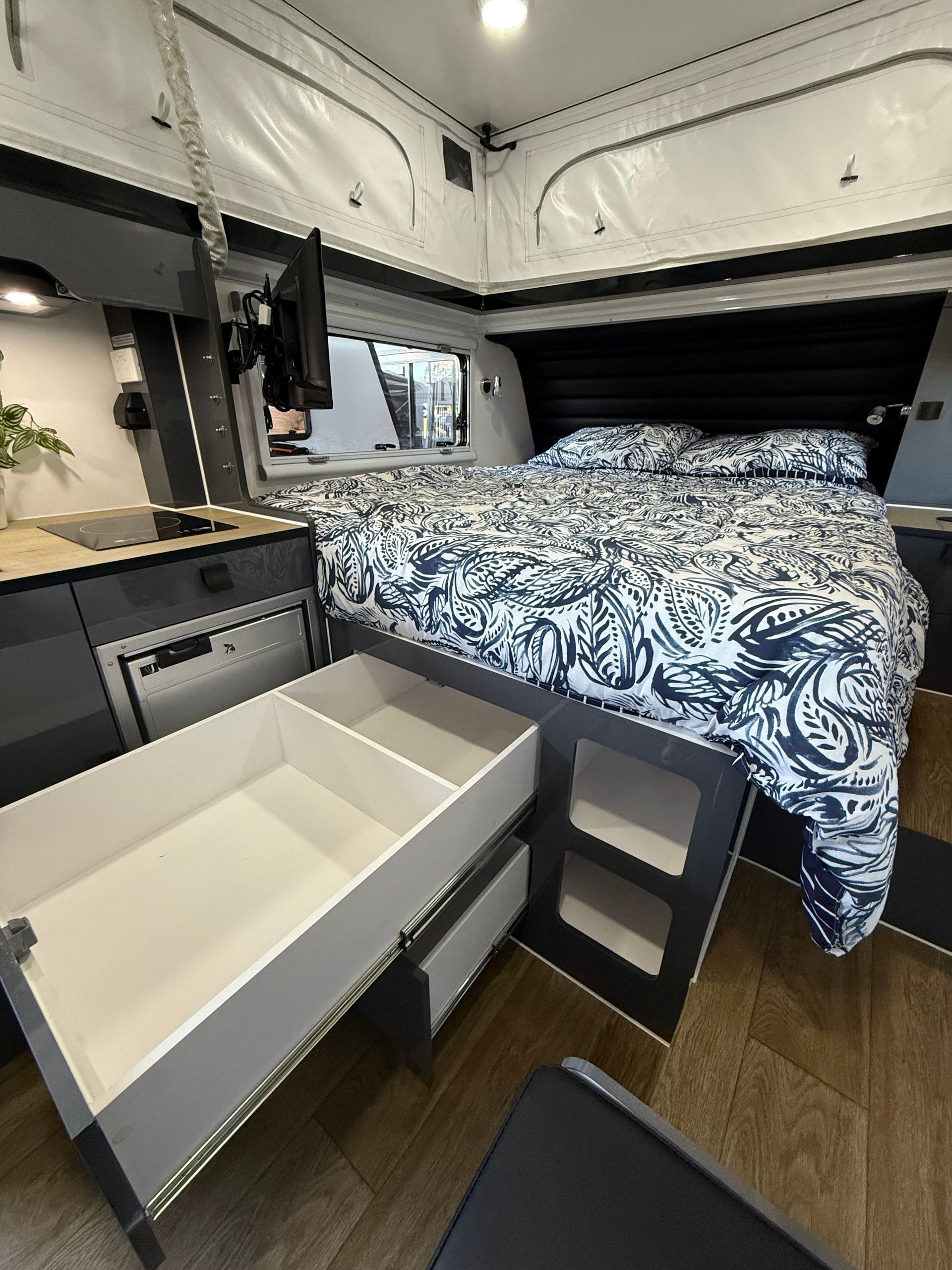 A bed in a camper with drawers underneath it.