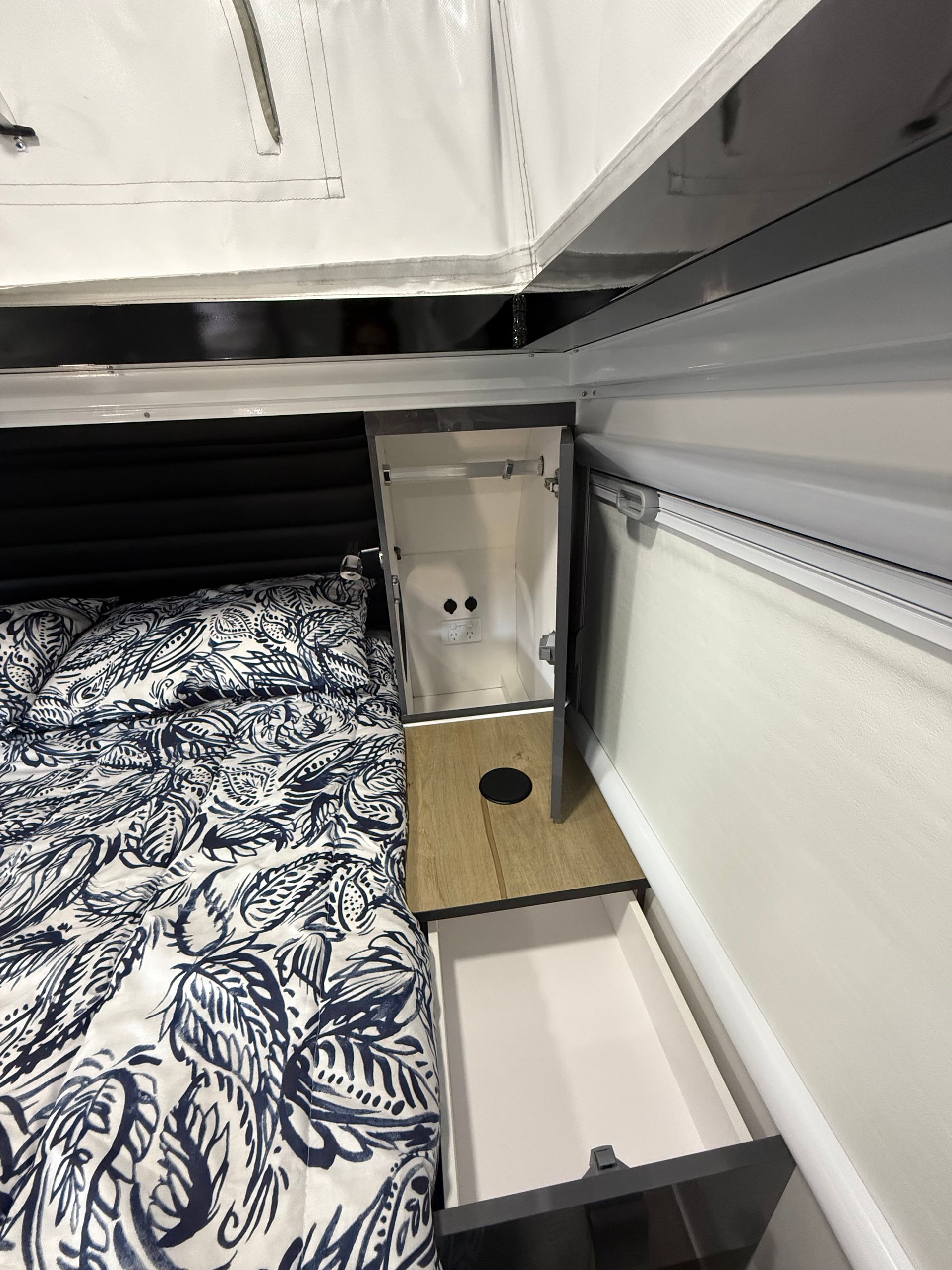 A box with a hole in it is sitting on a bed next to a drawer.