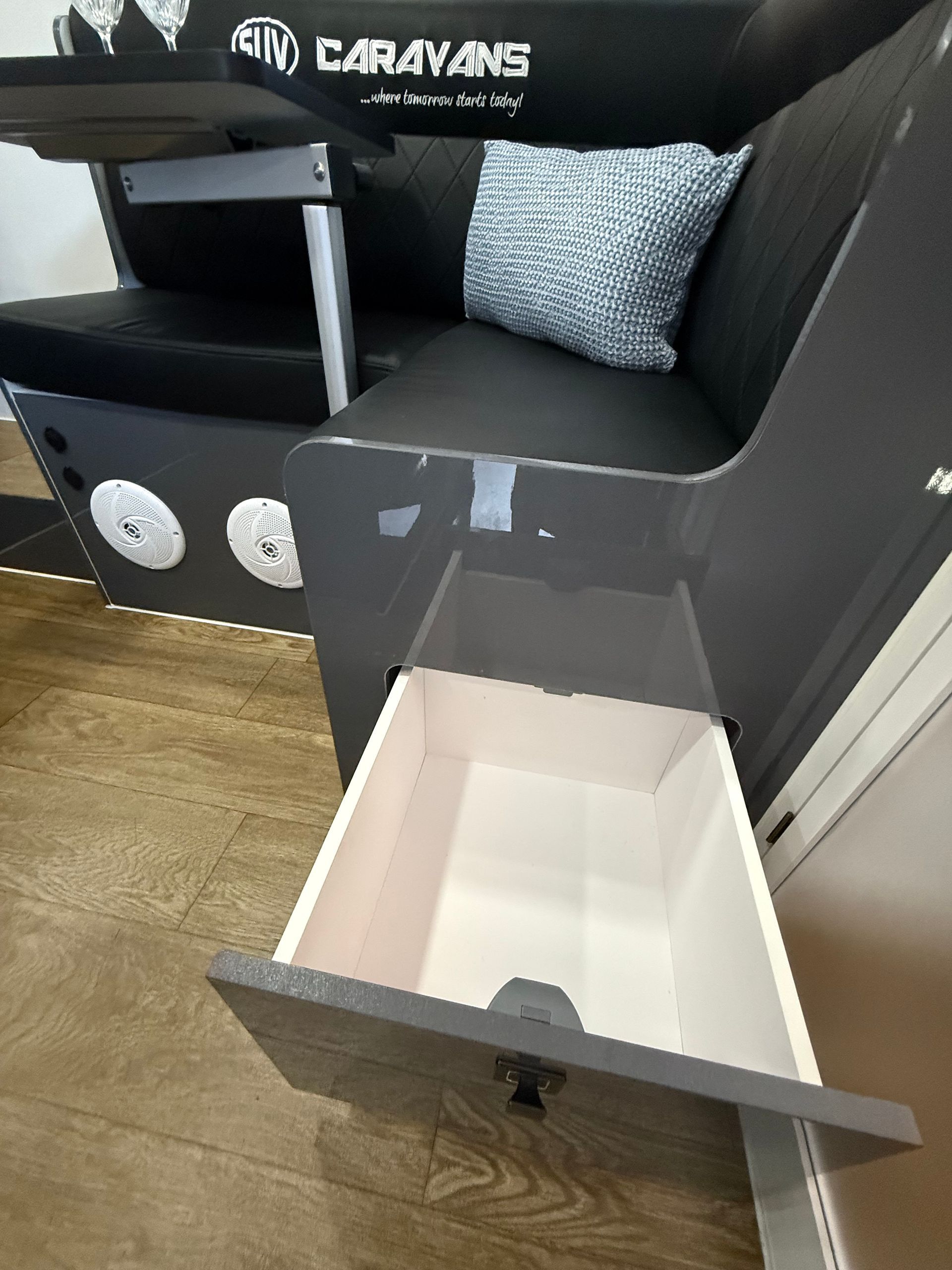 A chair with a drawer underneath it and a pillow on it.