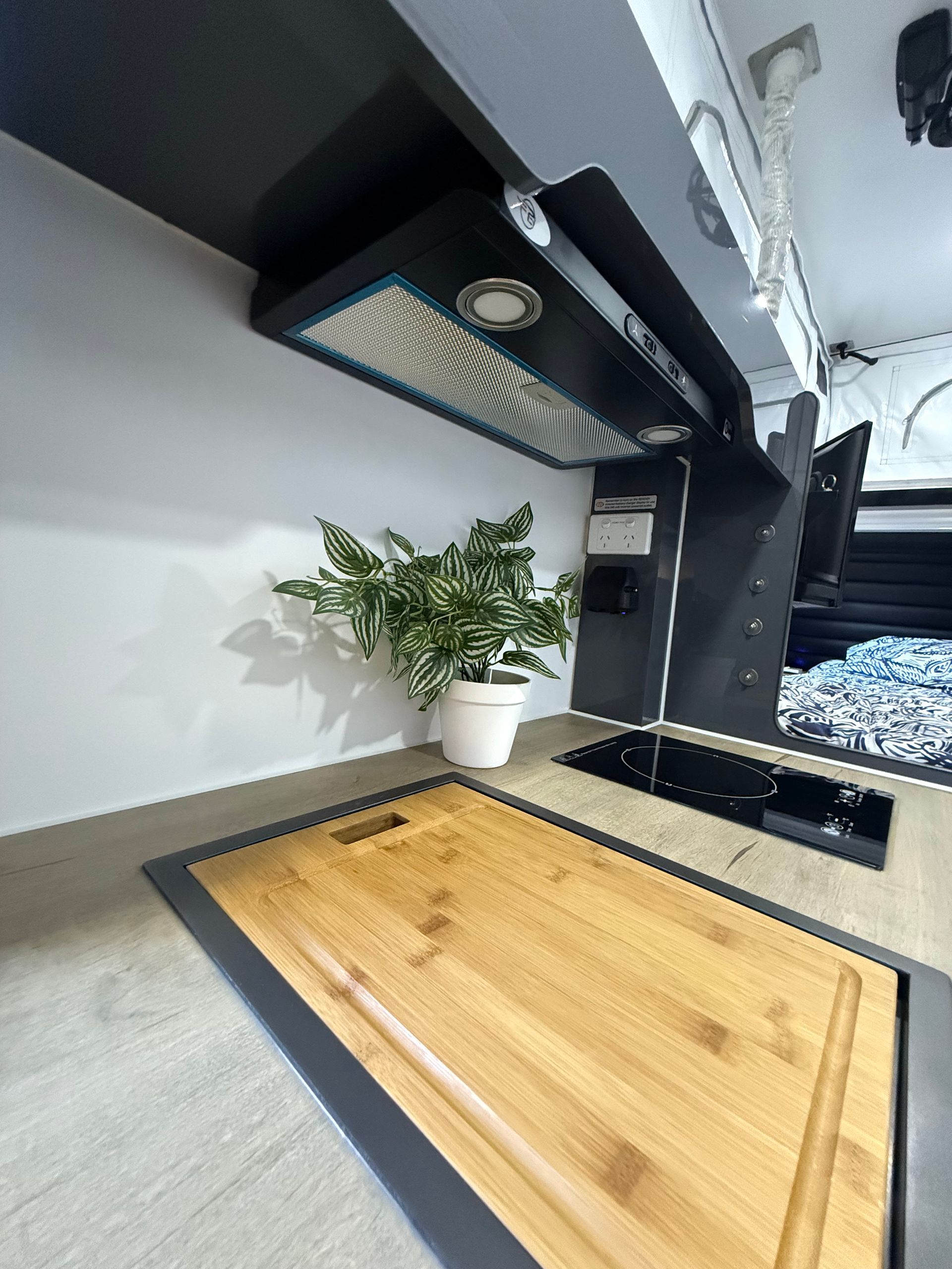 A kitchen with a wooden cutting board and a potted plant.