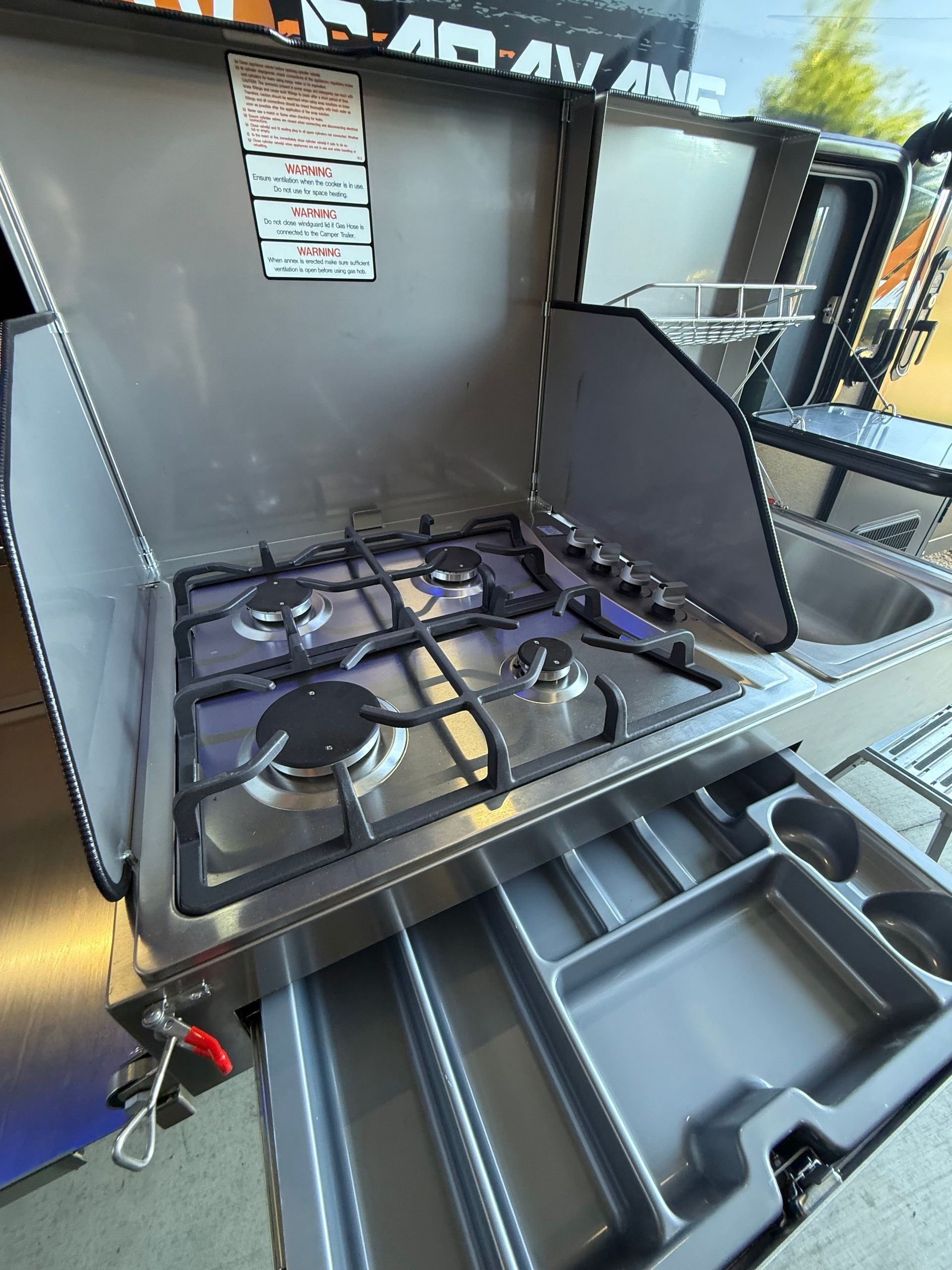 A stove with the lid open and a sink underneath it.