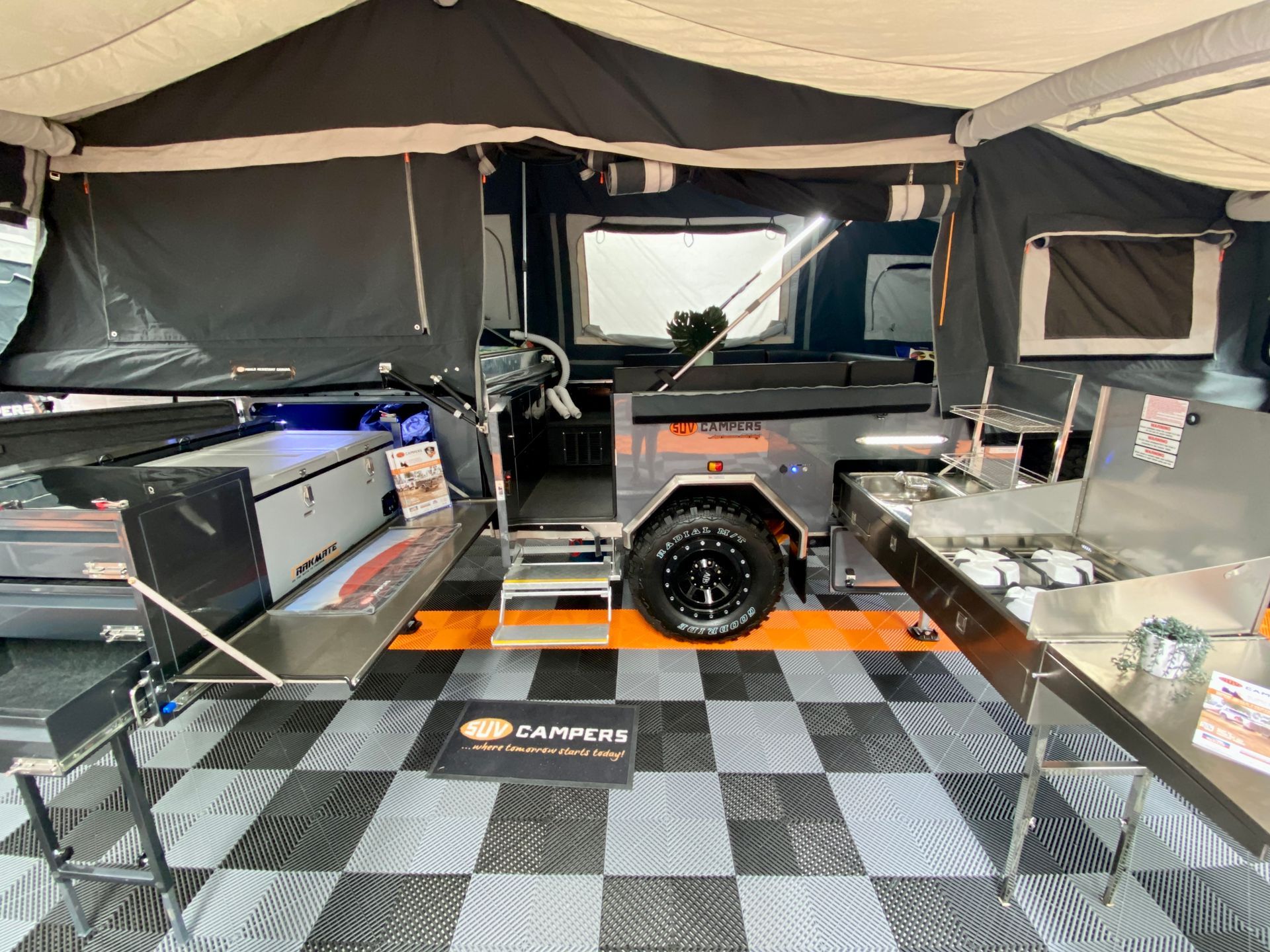 A camper trailer is parked in a garage with a checkered floor.