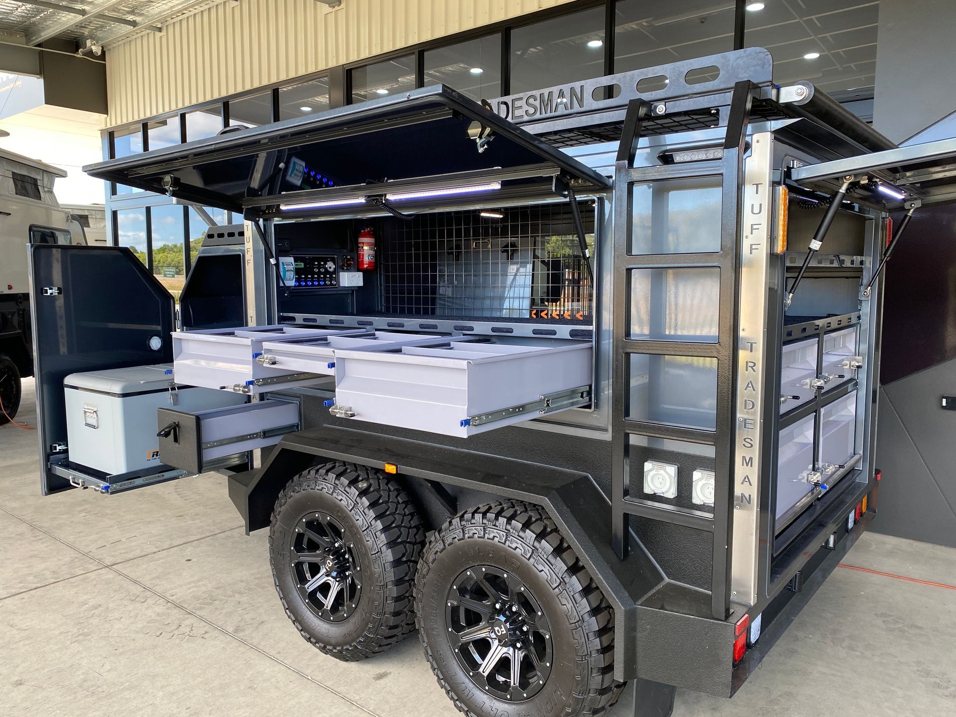A trailer with the doors open is parked in front of a building.