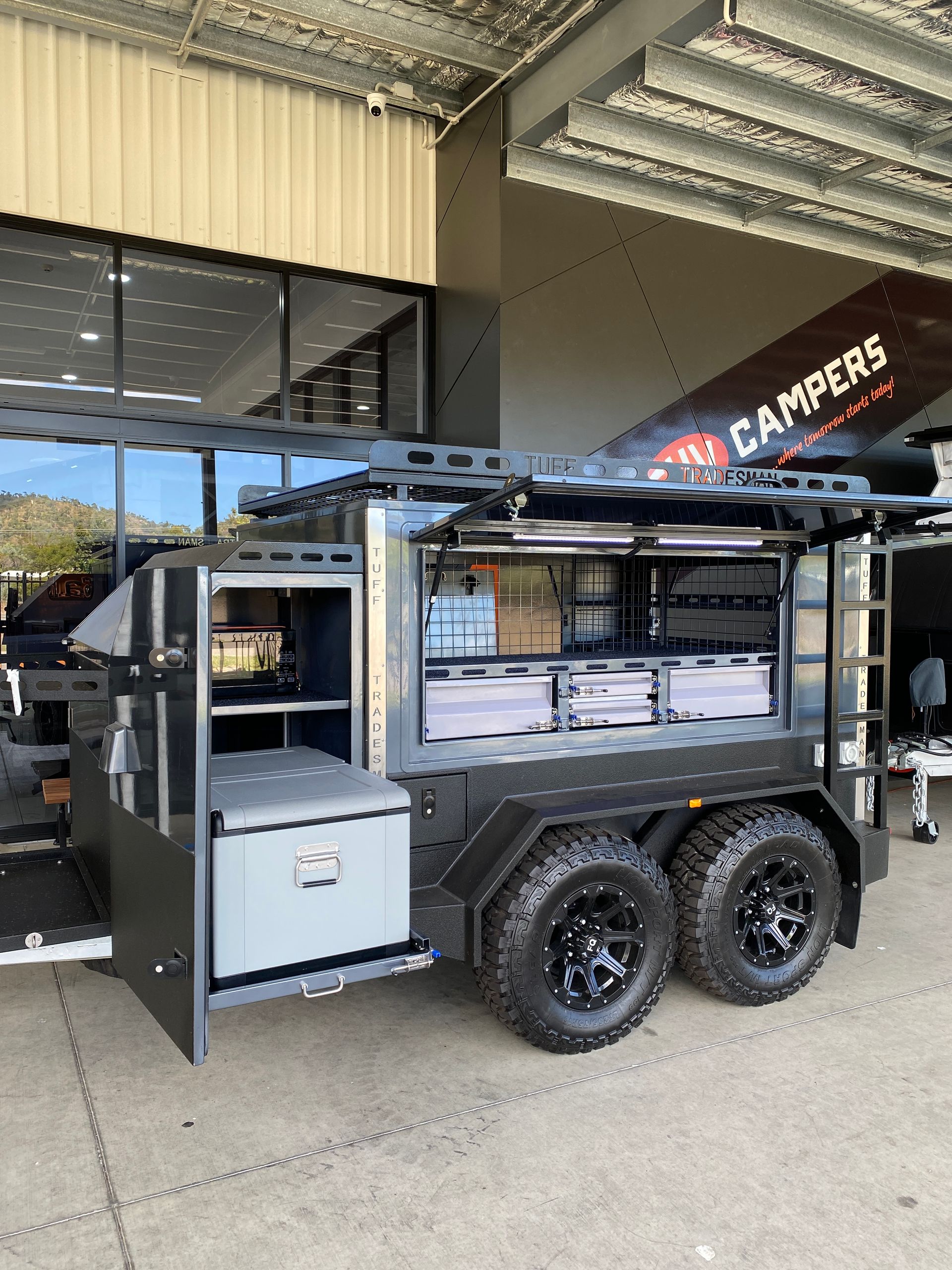 A trailer with the doors open is parked in front of a building.