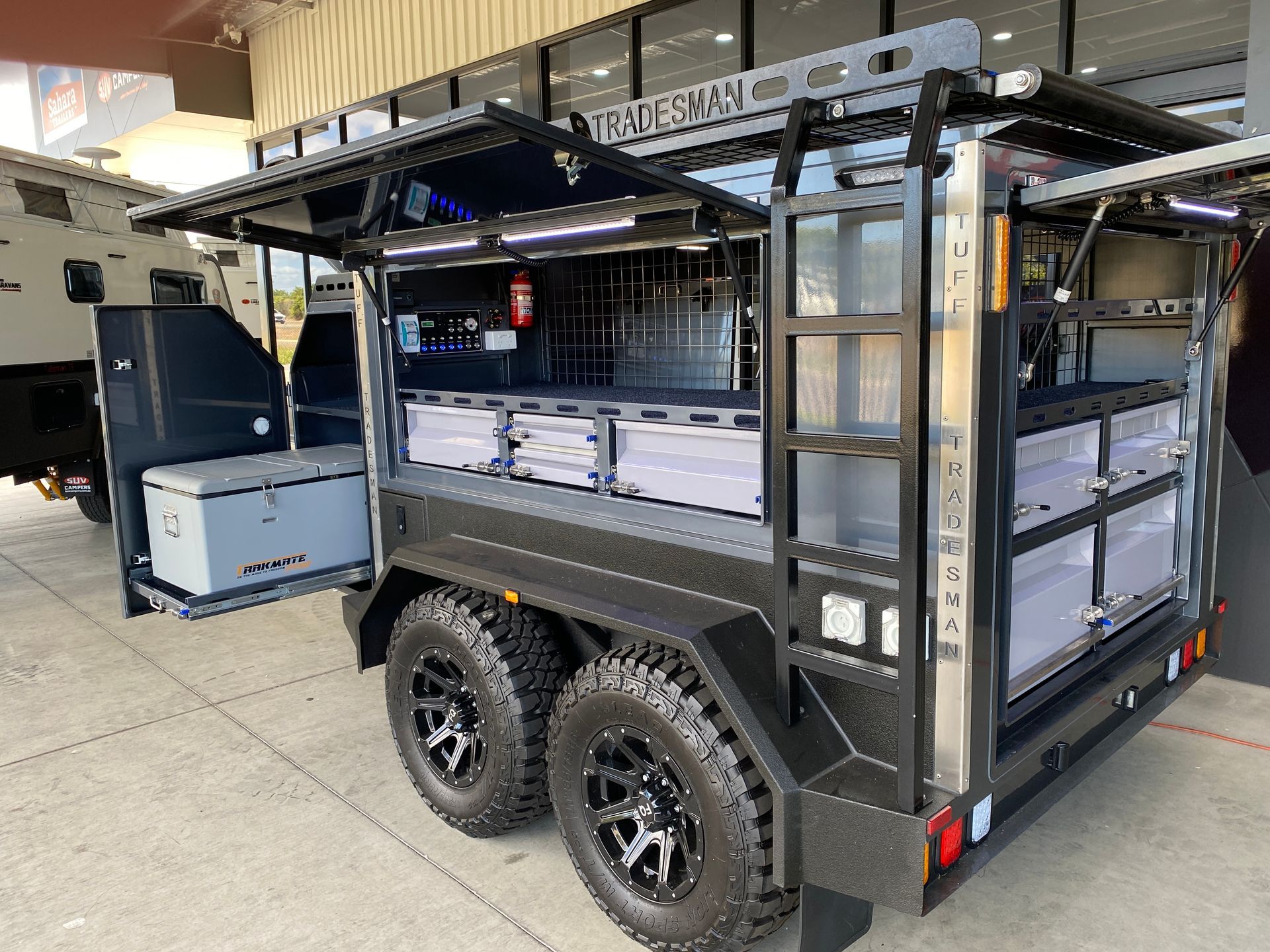 A black trailer with the doors open is parked in a parking lot.
