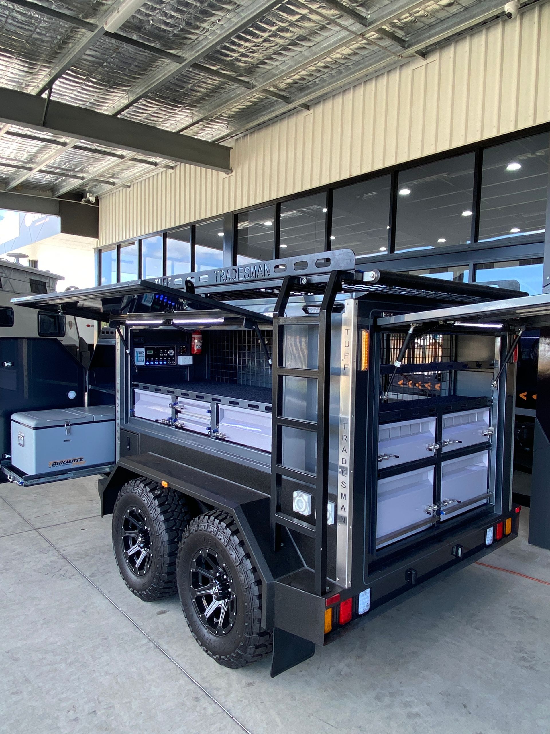 A black trailer is parked in front of a building.