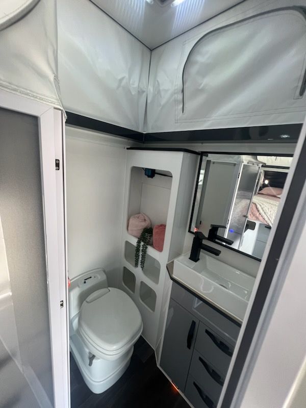 A bathroom with a toilet , sink and mirror.