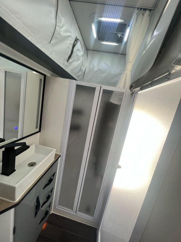 A bathroom with a sink , mirror and shower.