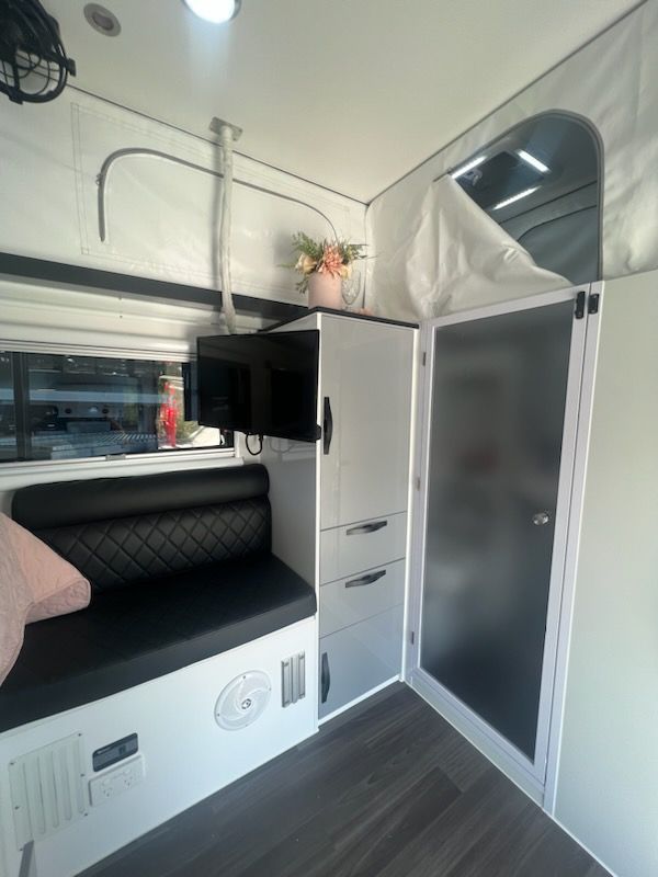 The inside of a camper with a couch and a tv.