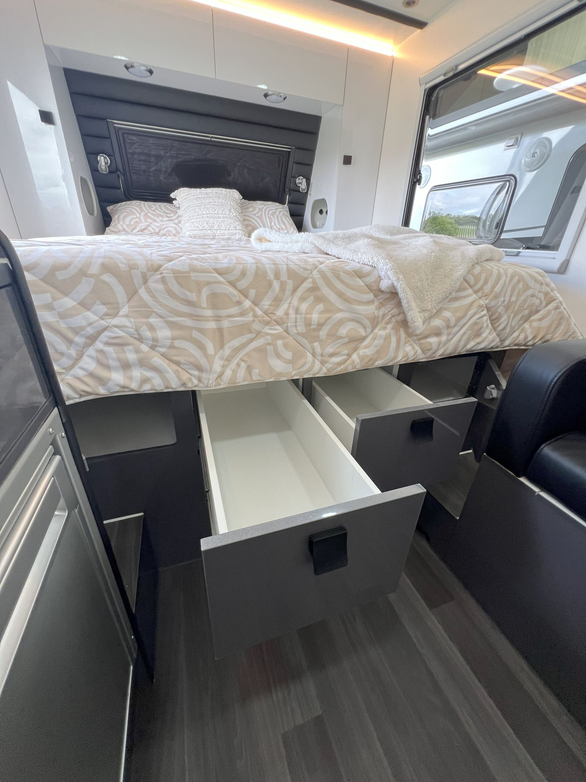 A bed with drawers underneath it in a camper van.