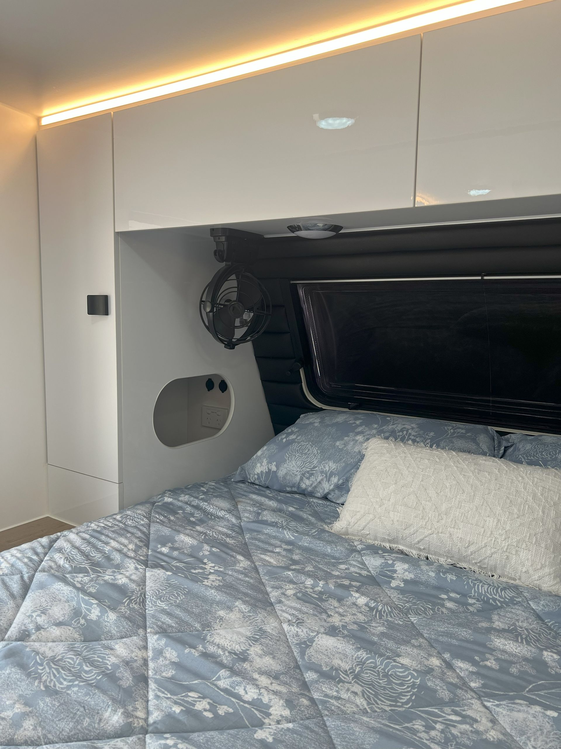 A bedroom in a camper with a bed and a fan.