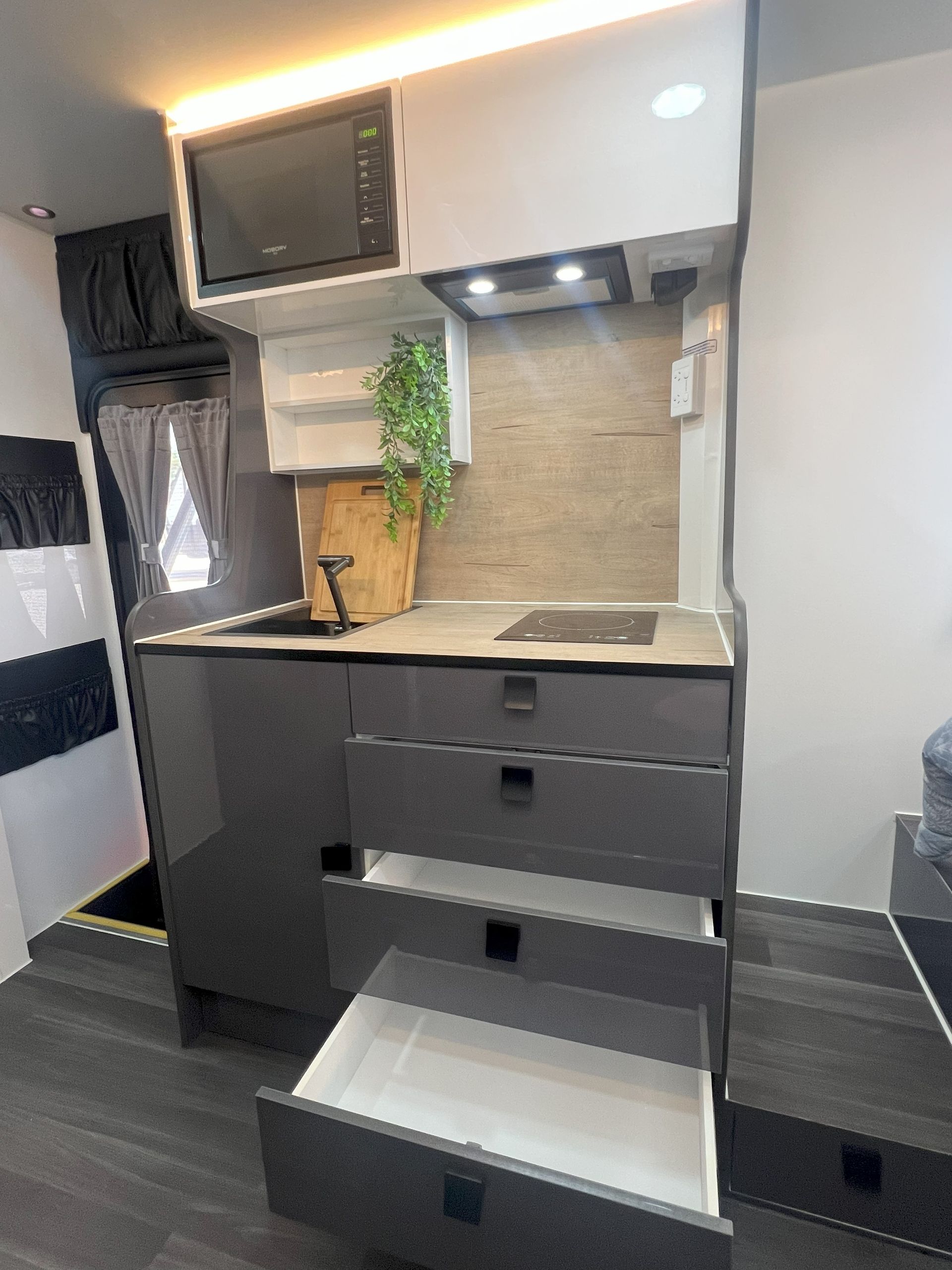 A kitchen in a camper with drawers open and a microwave.